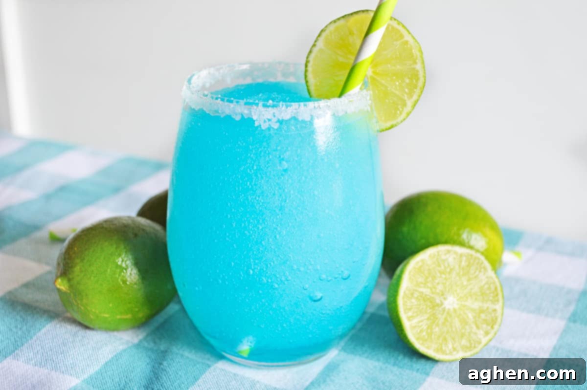 Azure Bliss Margaritas 3 Blue lagoon margarita served in stemless glass rimmed with sugar and garnished with a slice of lime.