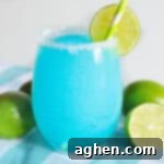 Azure Bliss Margaritas 5 Blue lagoon margarita served in stemless glass rimmed with sugar and garnished with a slice of lime.
