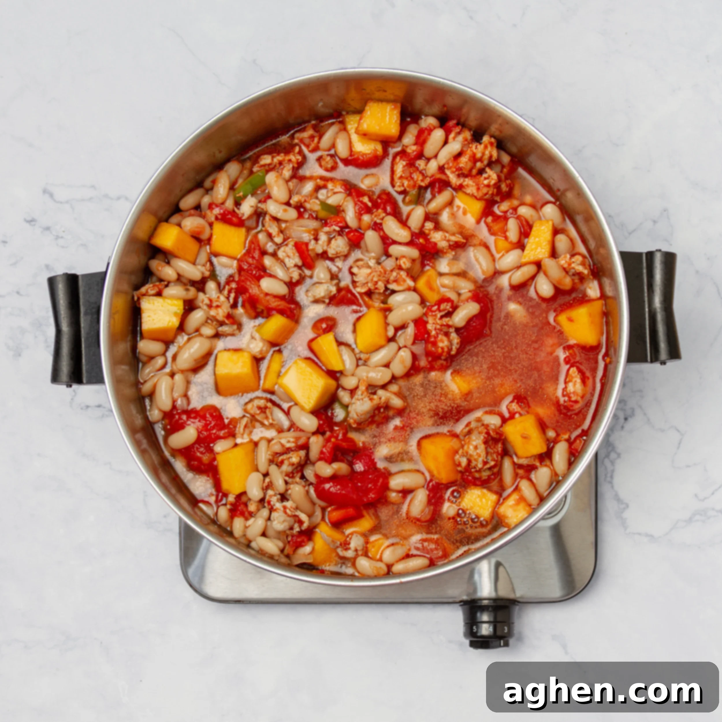 Al chili ingredients simmering in broth in a pot. 