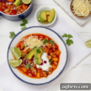 Chunky and delicious Turkey Pumpkin Chili in a bowl, topped with Greek yogurt, fresh limes, and cilantro.