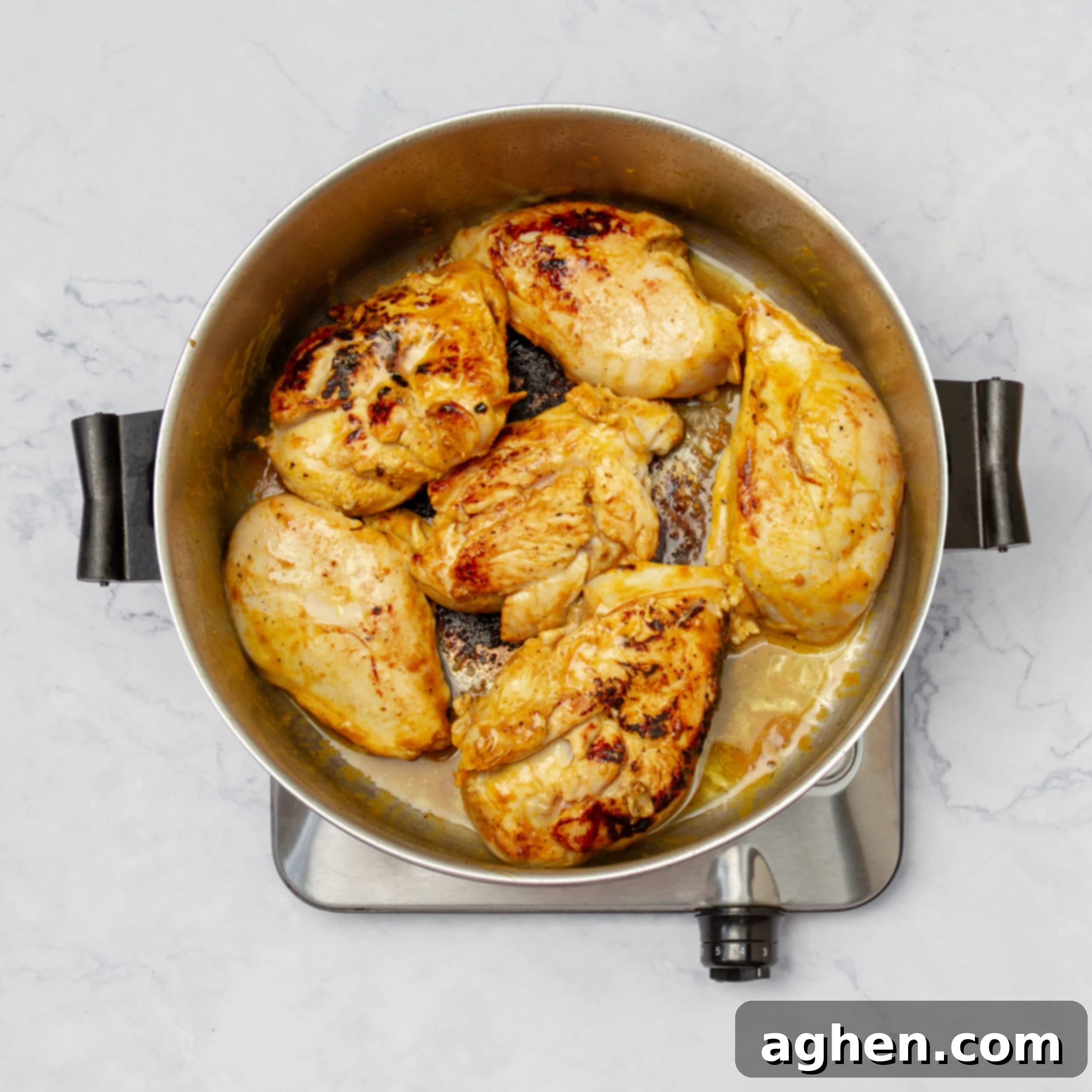 Chicken searing in a hot pan, developing a golden-brown crust.