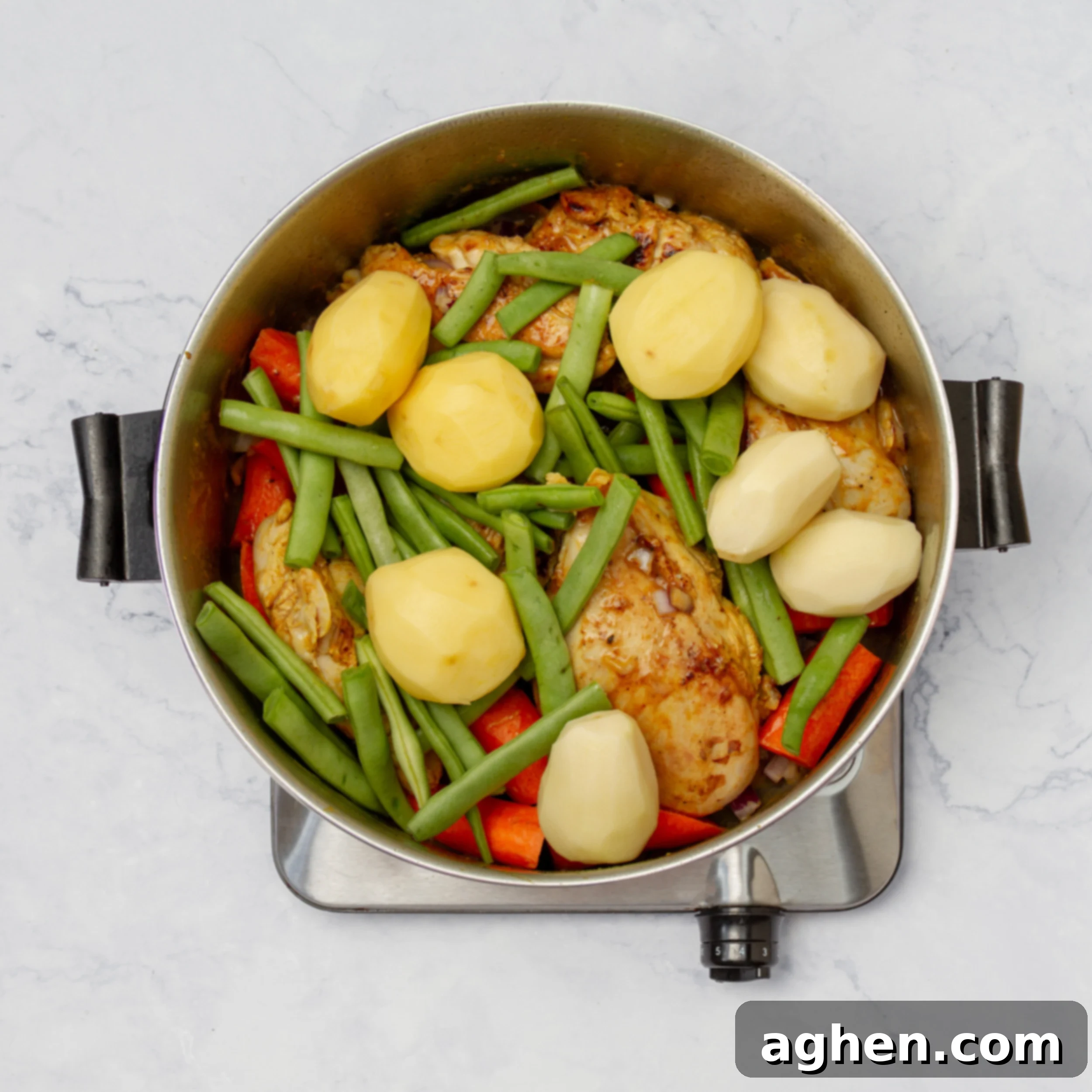Vegetables added to the pan alongside the cooked chicken, ready to be sautéed.