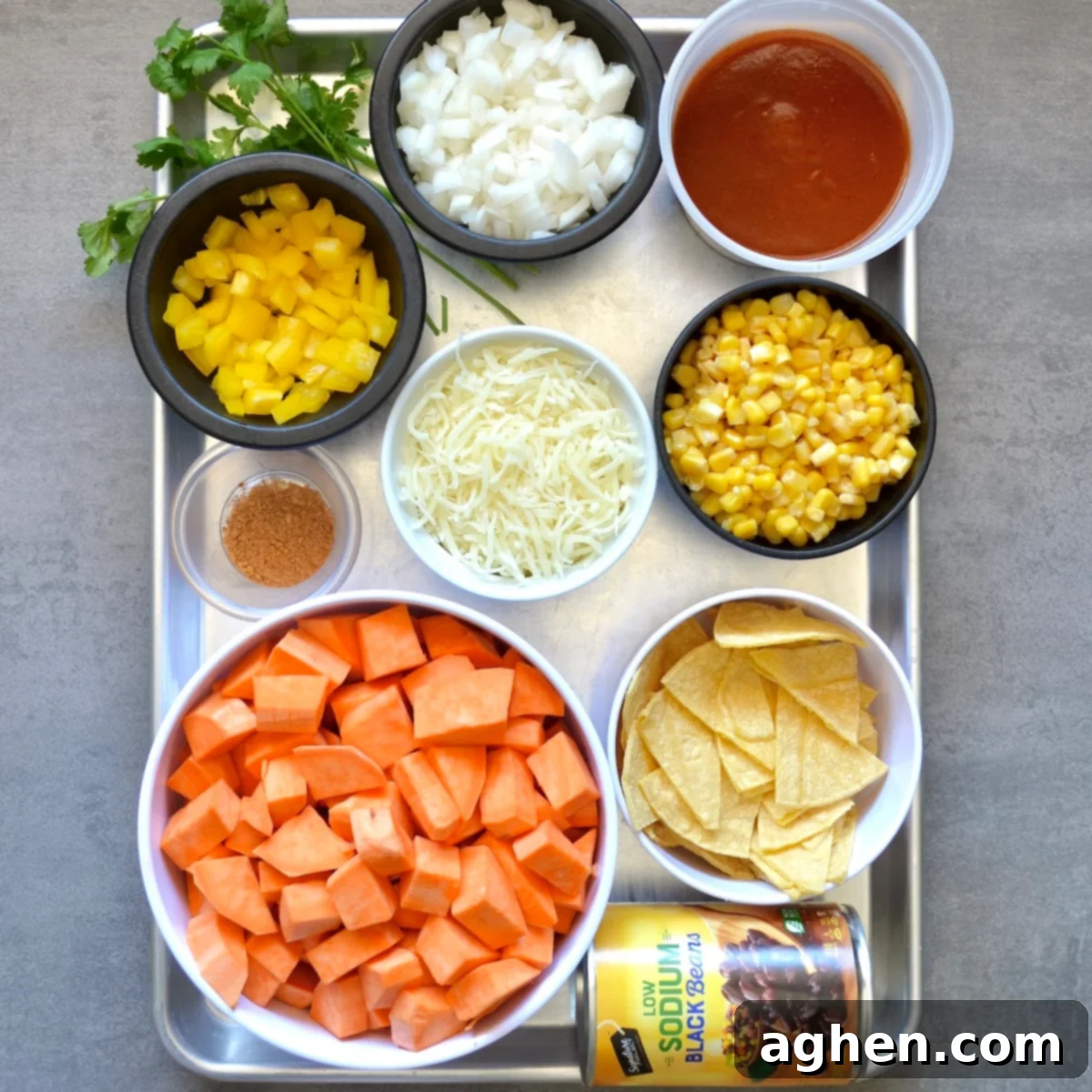 Close-up of fresh ingredients for sweet potato and black bean casserole: sweet potatoes, bell pepper, onion, corn, and black beans.