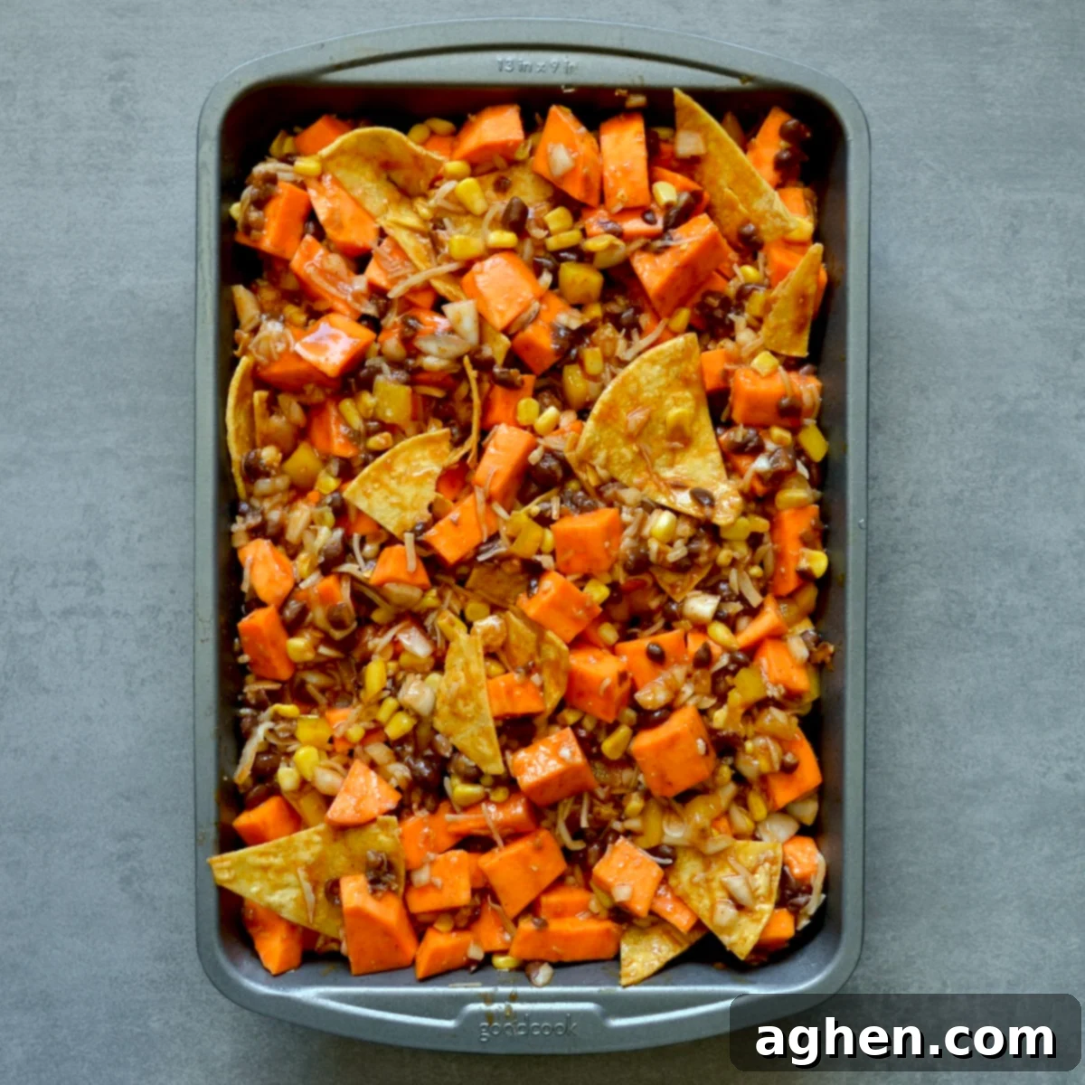 Sweet potato black bean enchilada casserole mixture spread evenly in a greased baking dish, ready for the oven.