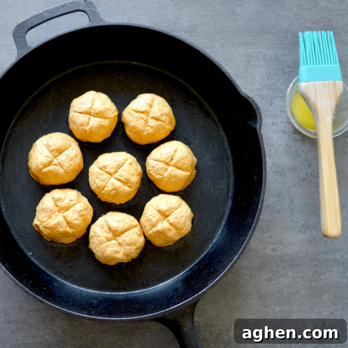 Unbaked pumpkin dinner rolls arranged in a buttered cast iron skillet before baking