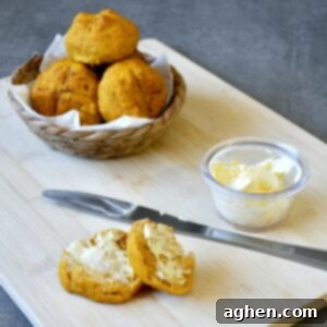 Pumpkin dinner rolls with a pat of butter on a plate, ready to be served