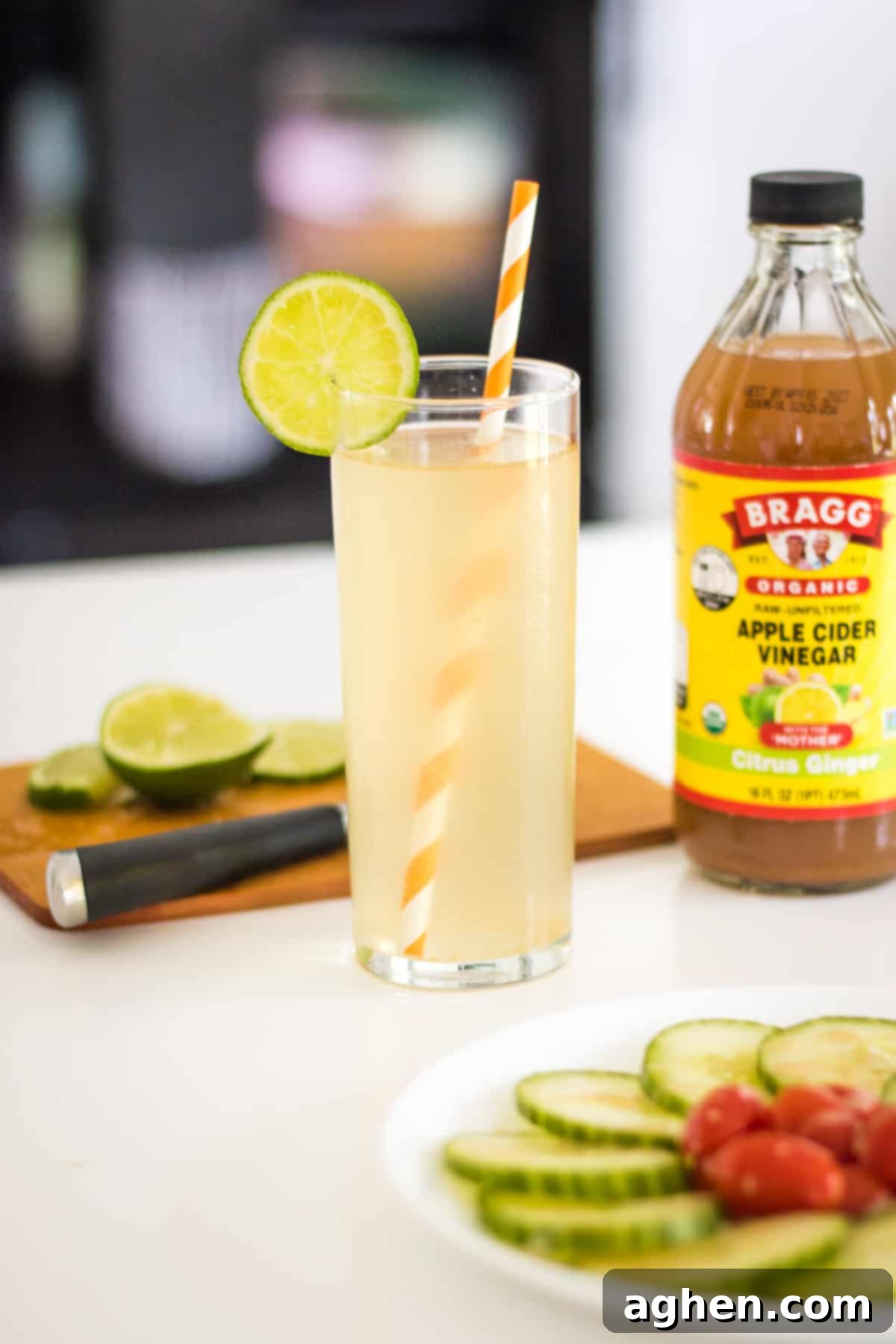 Zesty Apple Cider Tonic 2 Apple cider vinegar mocktail with sparkling water and fresh lime. Lime on a cutting board, cucumber salad, and a bottle of apple cider vinegar in the background