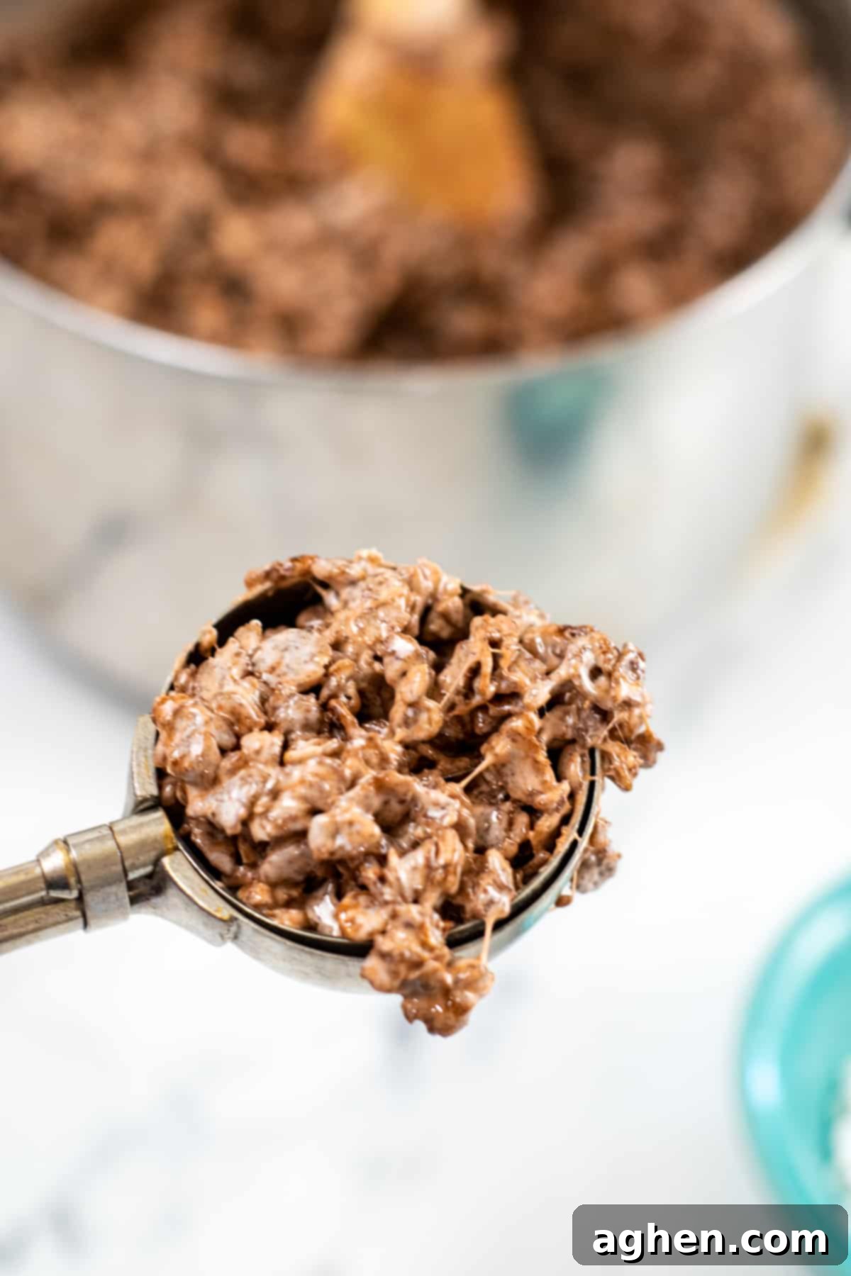 Frightfully Delicious Spider Bites 7 A scoop of cocoa krispie treat mixture in a hand, ready to be rolled into a ball.