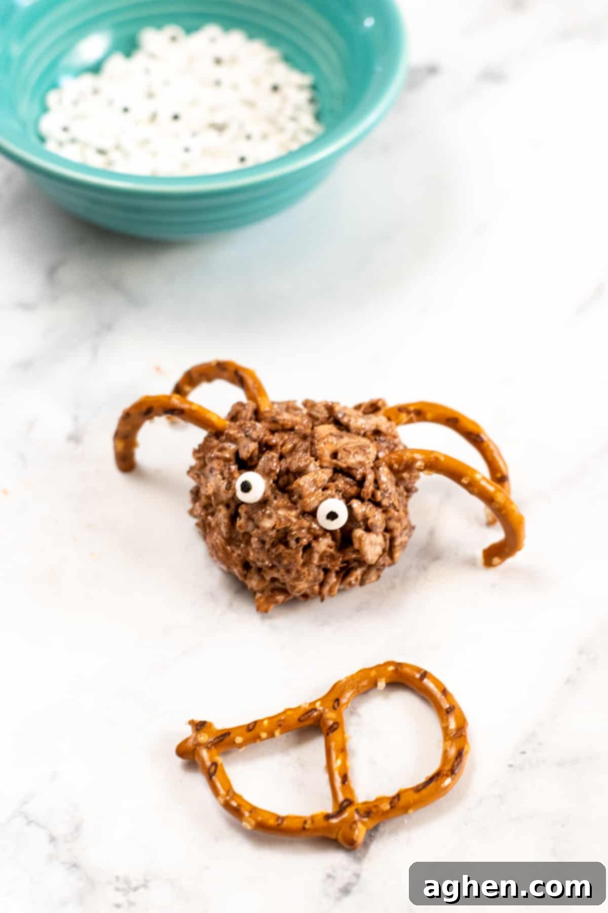 Frightfully Delicious Spider Bites 8 A round rice cereal treat with pretzel legs and candy eyes, demonstrating the decorating process for a spider treat.