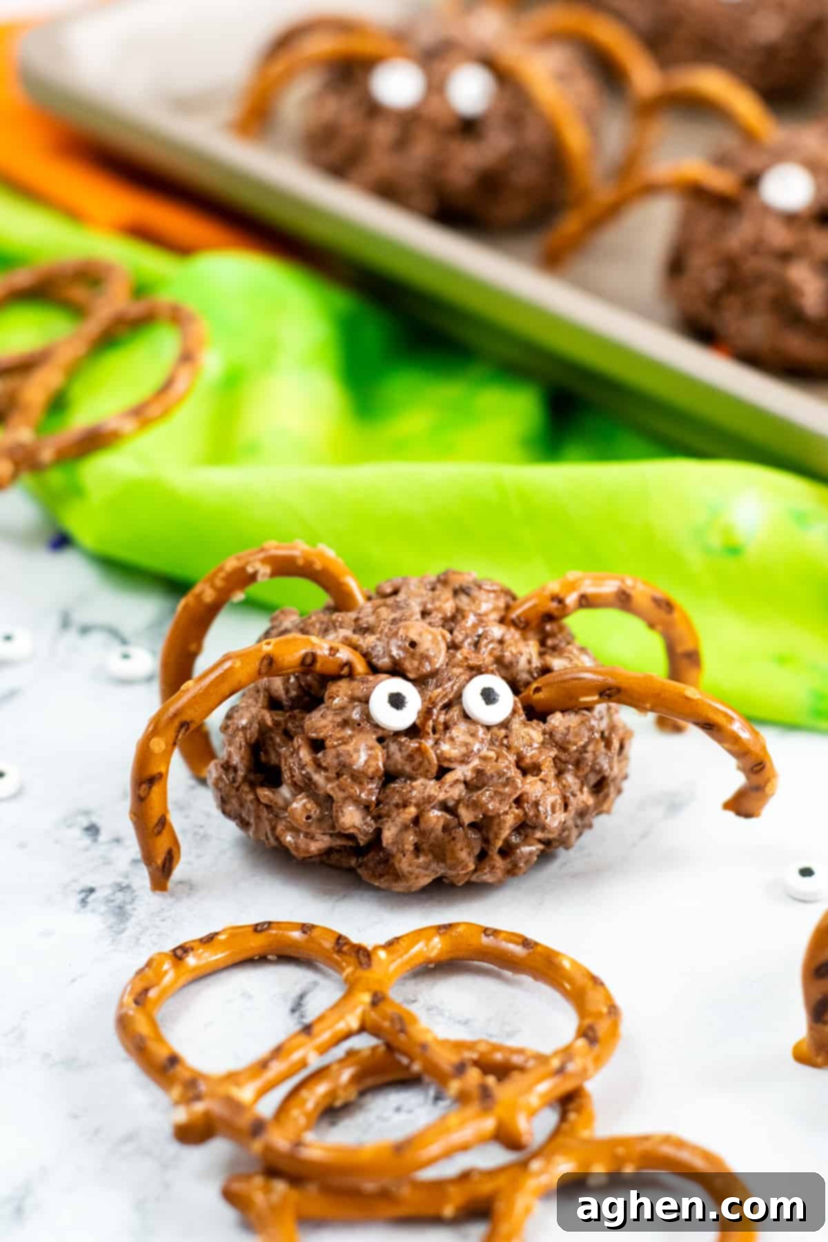 Frightfully Delicious Spider Bites 9 Brown rice krispies treat spiders with pretzel pieces as legs and candy eyes, arranged on a black serving tray.