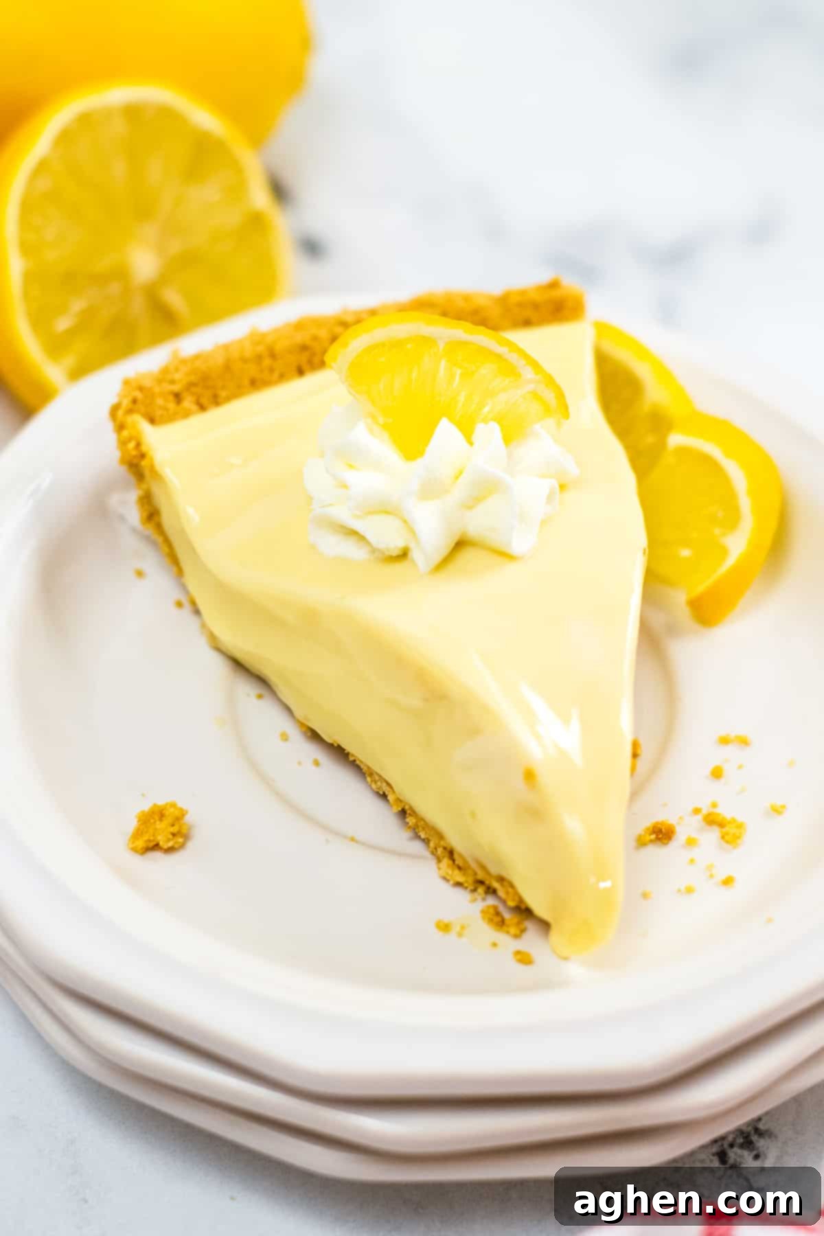Zesty Lemon Icebox Pie 3 Piece of no bake lemon pie with graham cracker crust and topped with lemon slice and whipped cream