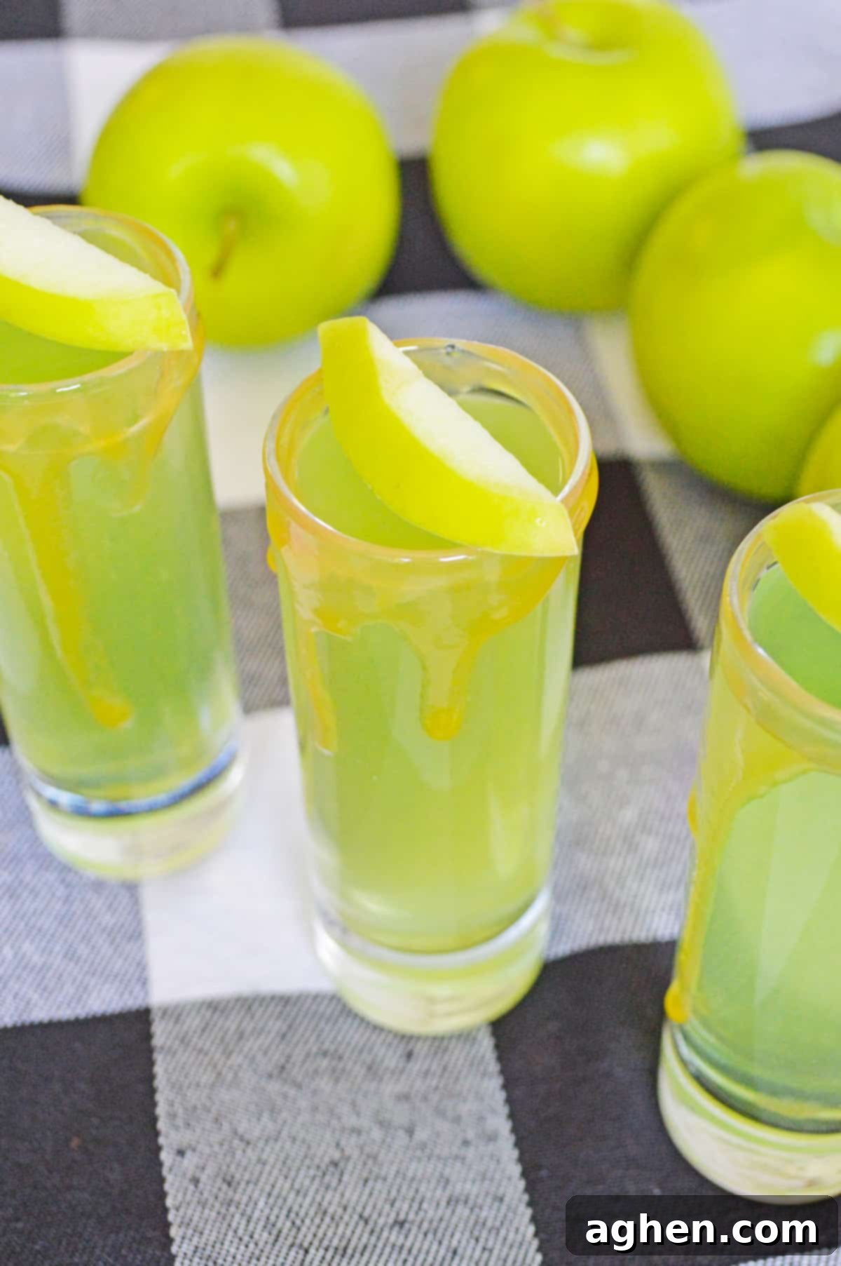 Decadent Caramel Apple Shots 4 Caramel Apple Vodka Shots garnished with caramel drizzle and fresh apple slices.
