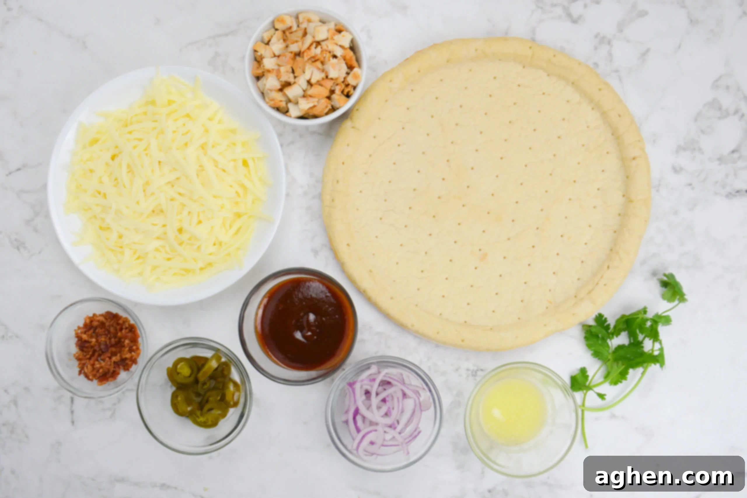 The ingredients to make Blackstone pizza are placed next to the crust in small bowls. 