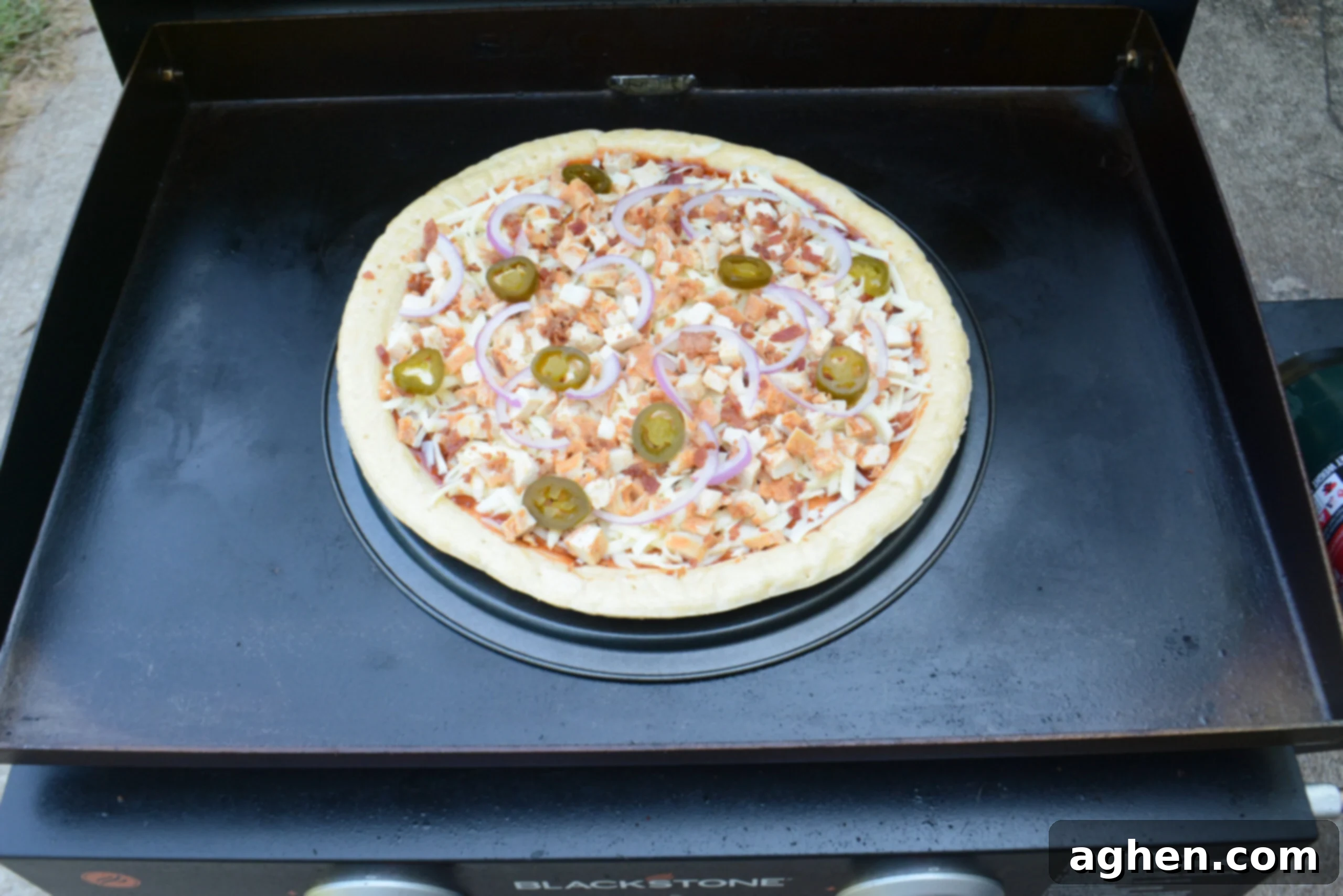 The pizza is shown on a Blackstone griddle on top of an upside down pizza pan.
