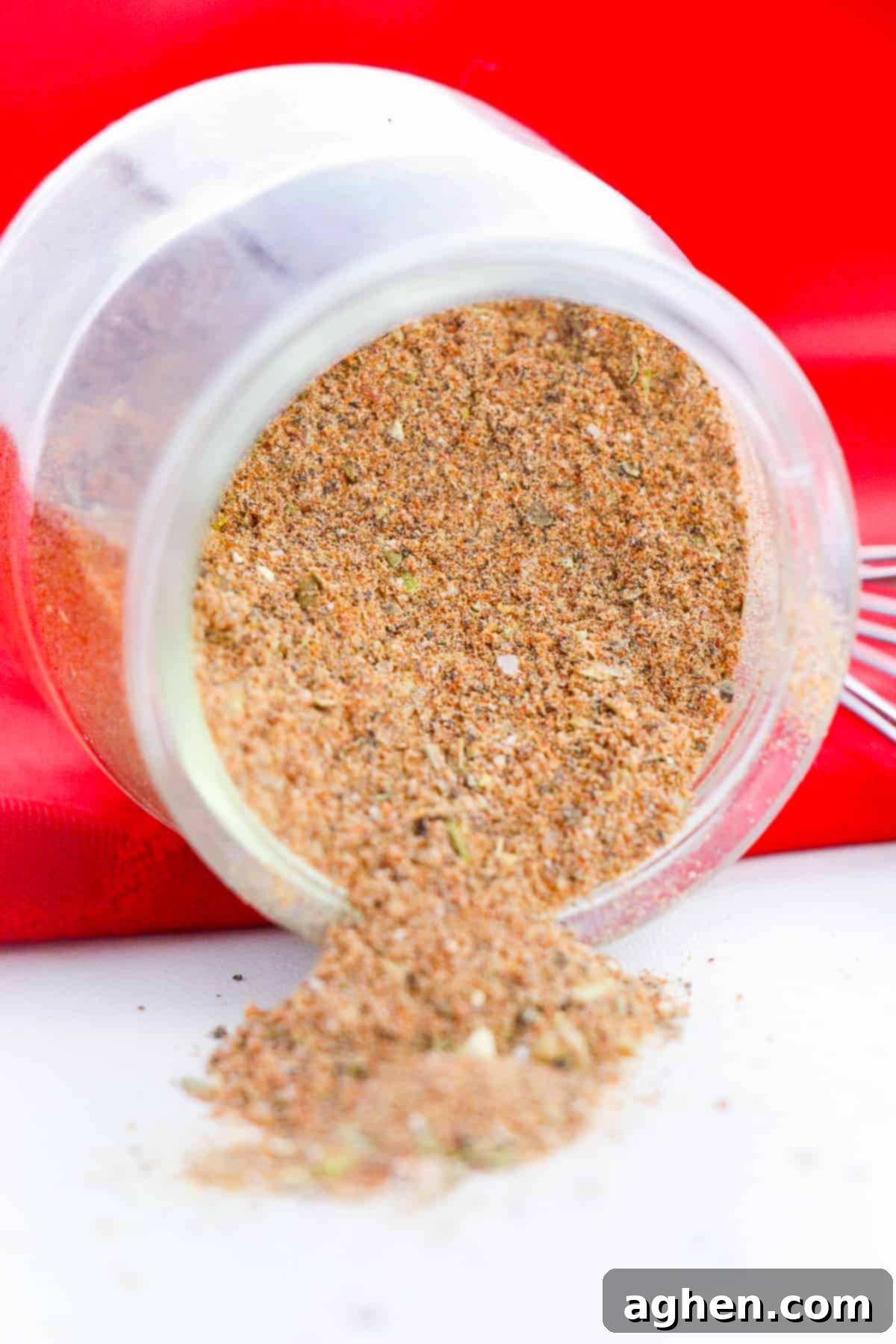 Jar of homemade chili seasoning mix laying down on its side with the seasoning falling out onto tabletop