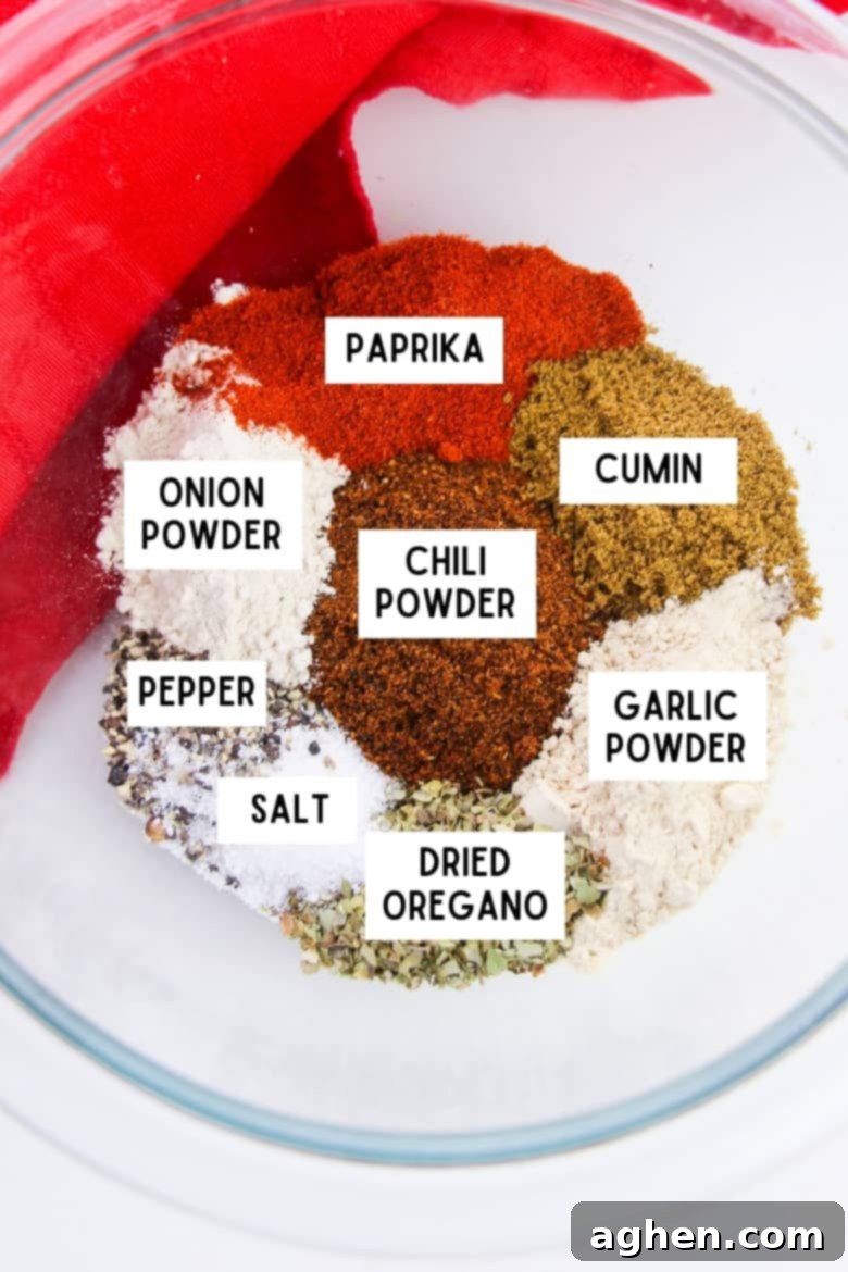Ingredients for chili seasoning mix in bowl: paprika, cumin, garlic powder, dried oregano, salt, pepper, chili powder, and onion powder.
