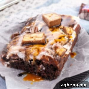Snickers poke cake made with chocolate cake, chocolate pudding, caramel sauce, peanuts, chocolate sauce, chocolate pudding, and chopped Snickers candy bars.