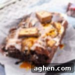 Snickers poke cake made with chocolate cake, chocolate pudding, caramel sauce, peanuts, chocolate sauce, chocolate pudding, and chopped Snickers candy bars.