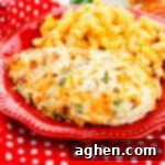 Jalapeño popper chicken breast on a red plate with side of macaroni and cheese.