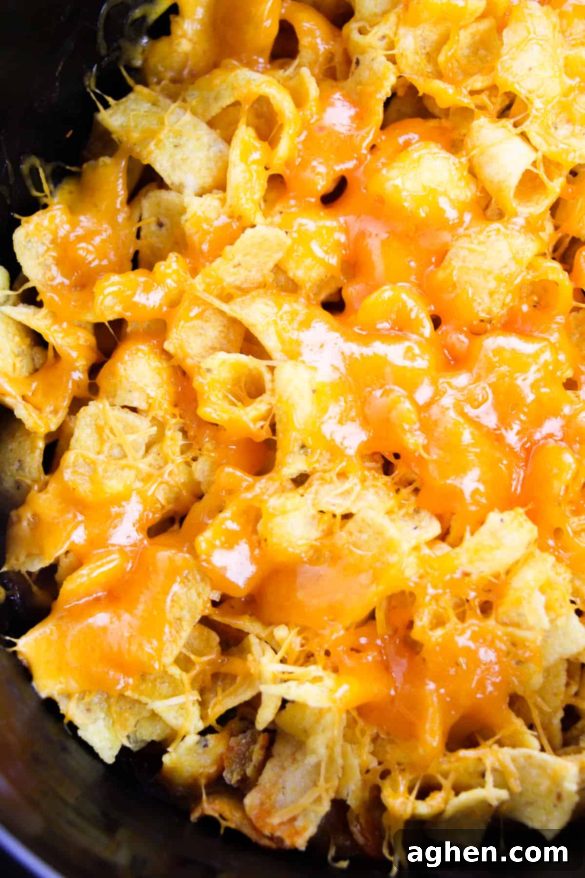Crockpot filled with the rich, savory Frito Pie mixture, generously topped with golden Fritos and freshly melted cheddar cheese, ready to be served.