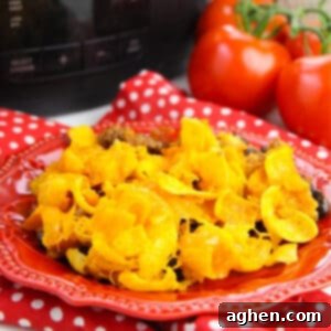 A delicious Crockpot Frito Pie, featuring layers of seasoned ground beef, beans, enchilada sauce, melted cheese, and crispy Fritos, presented as a savory comfort food meal.