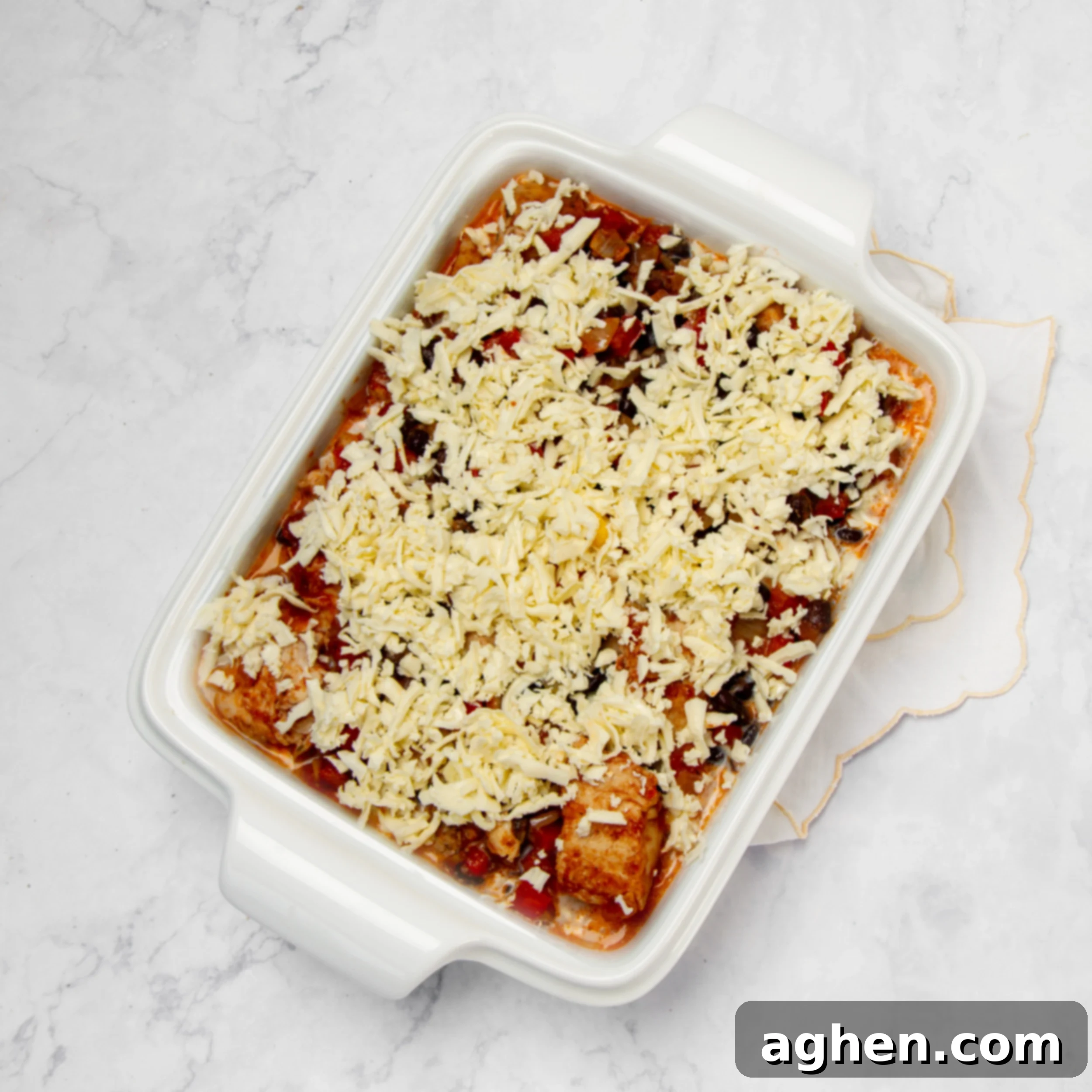 Your Go-To Weight Watchers Mexican Chicken Casserole 7 The assembled Mexican Chicken Casserole in a baking dish, with corn, chicken-vegetable mixture, soup, and cheese layers, ready for the oven.
