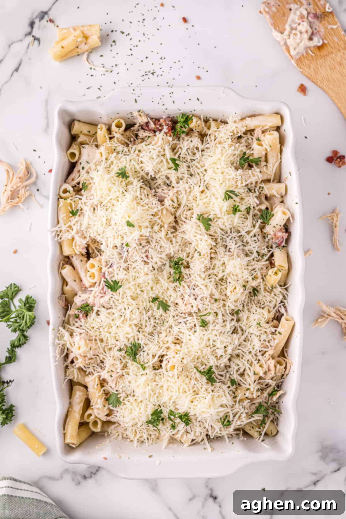 Unbaked chicken Alfredo casserole, topped with shredded cheese and parsley