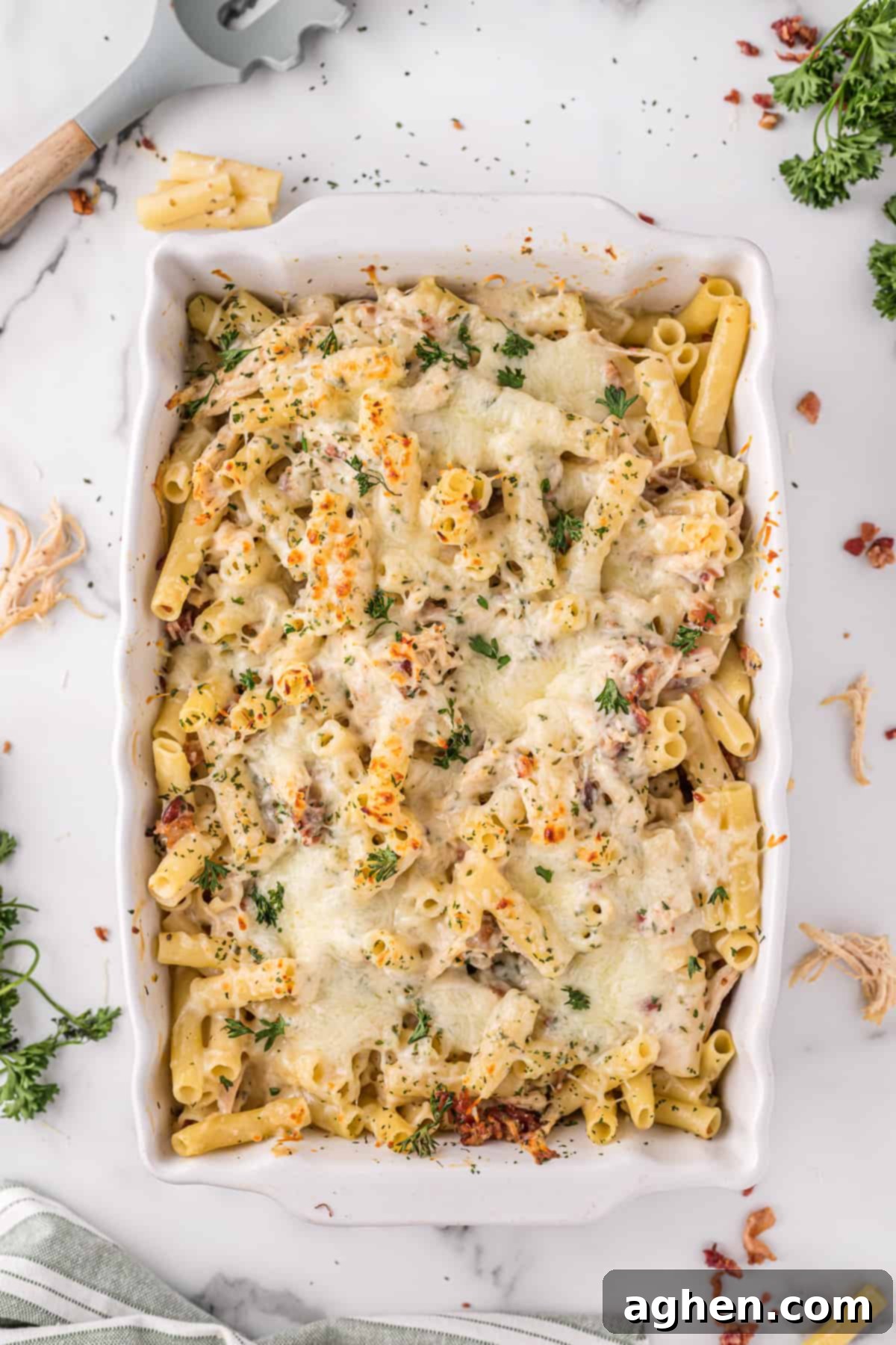 Chicken alfredo pasta bake with bacon and parsley on top, in a 9 x 13 casserole dish