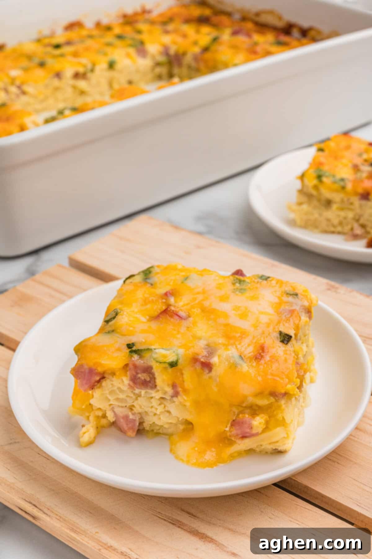 A slice of farmers casserole plated in front of the baking dish.
