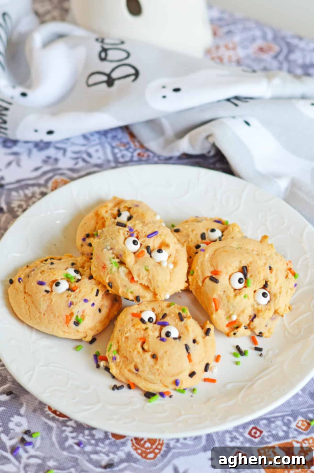 Orange Halloween cookies with sprinkles and eyeballs on a white plate
