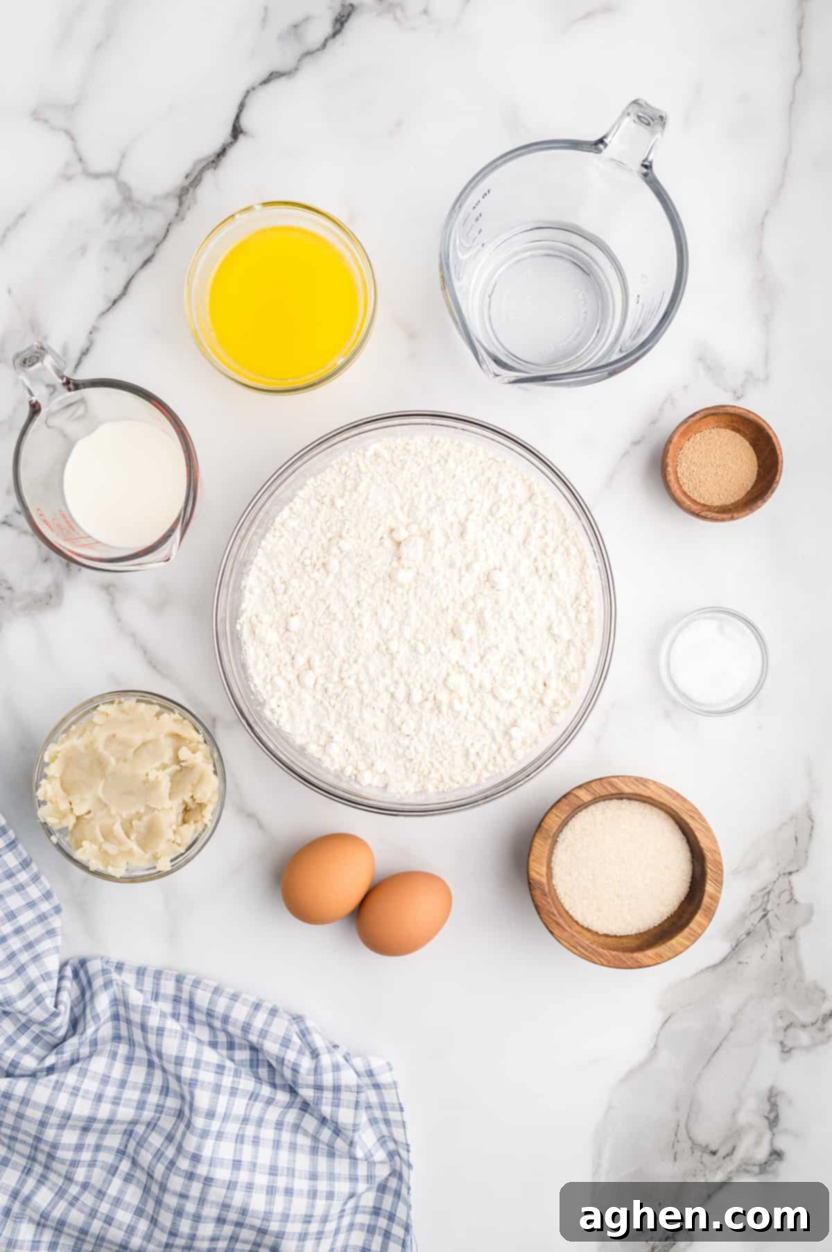 Ingredients for potato rolls on countertop: flour, melted butter, water, yeast, milk, granulated sugar, 2 eggs, salt, and mashed potatoes.