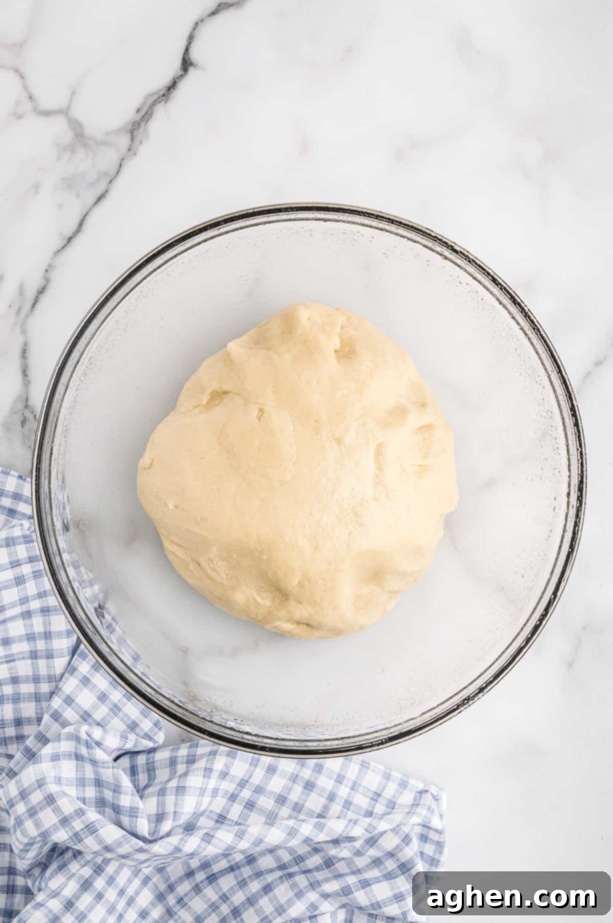 Potato roll dough rising in glass bowl