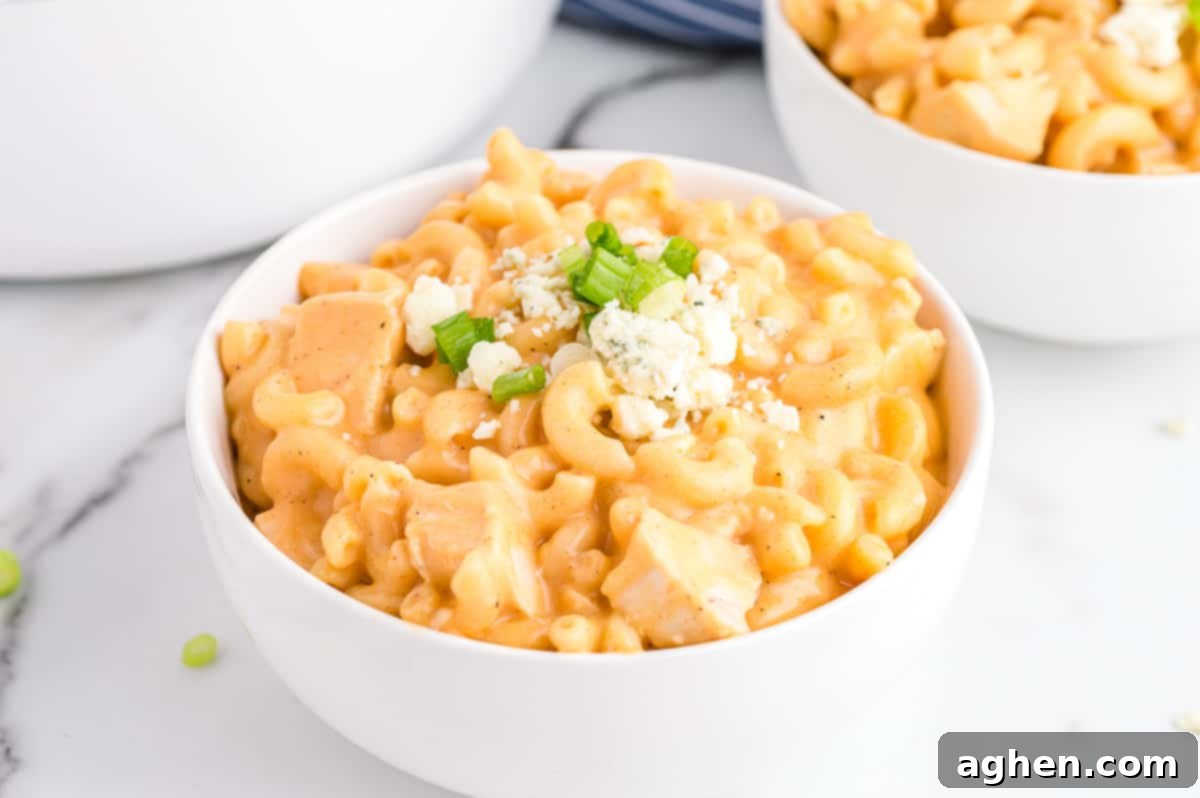 Buffalo Chicken Mac and Cheese in white bowl topped with blue cheese and scallions.