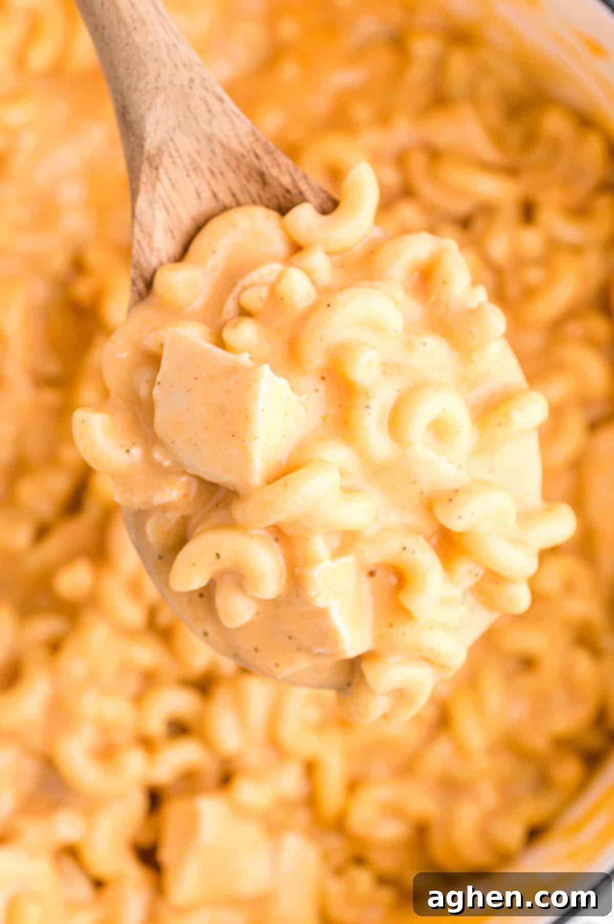 Wooden spoon lifting a spoonful of buffalo chicken mac and cheese out of large pot