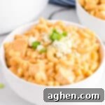 Buffalo Chicken Mac and Cheese in white bowl topped with blue cheese and scallions.