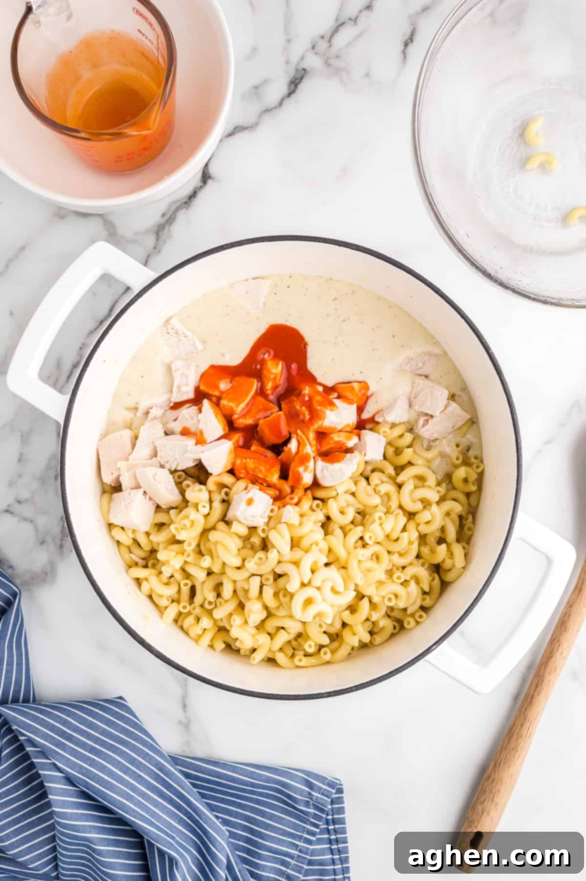 Macaroni, buffalo sauce, and chicken are added to pot of cheese sauce