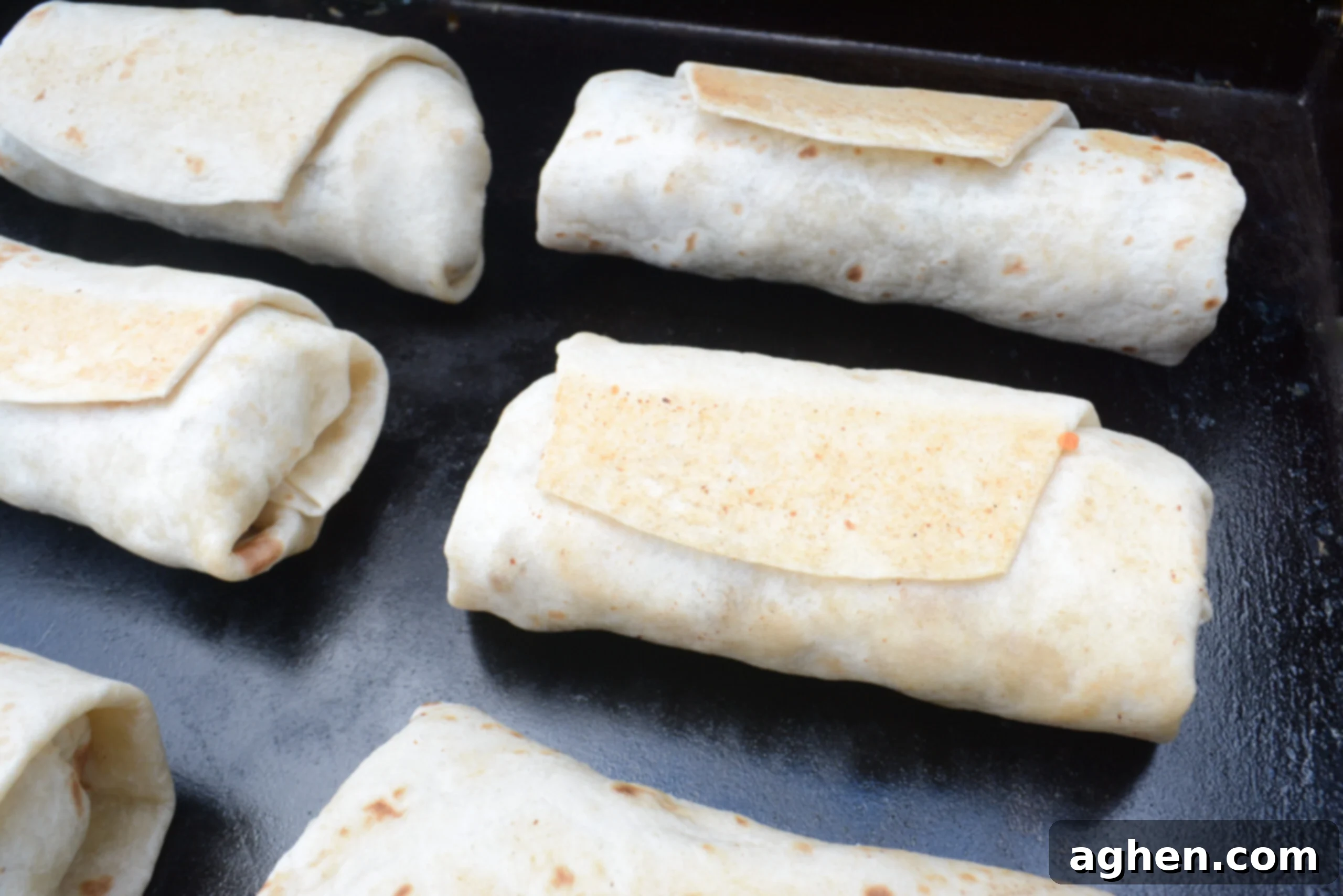 Browned burritos sit on top of the Blackstone. 