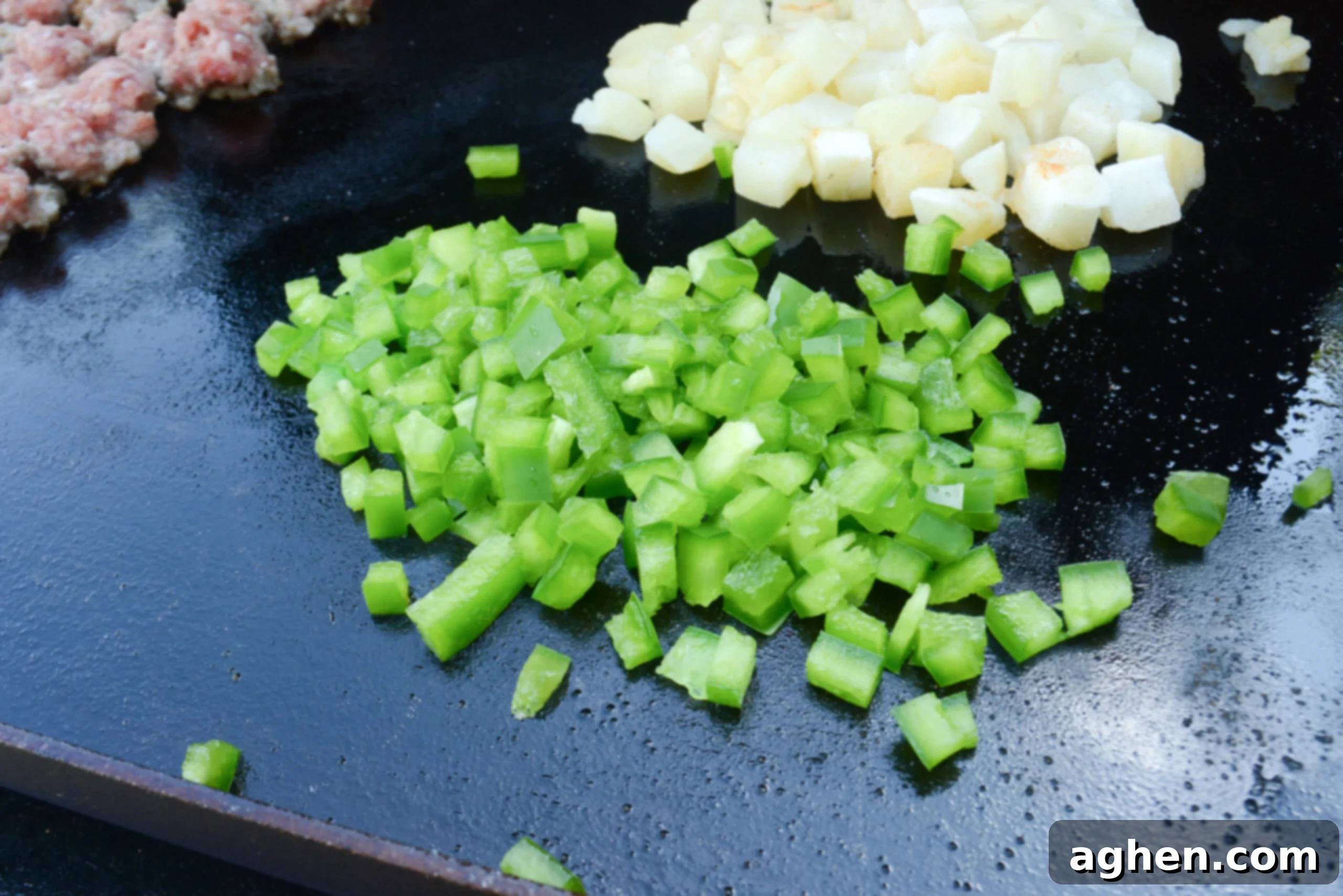 A close up of diced green bell pepper on the griddle.