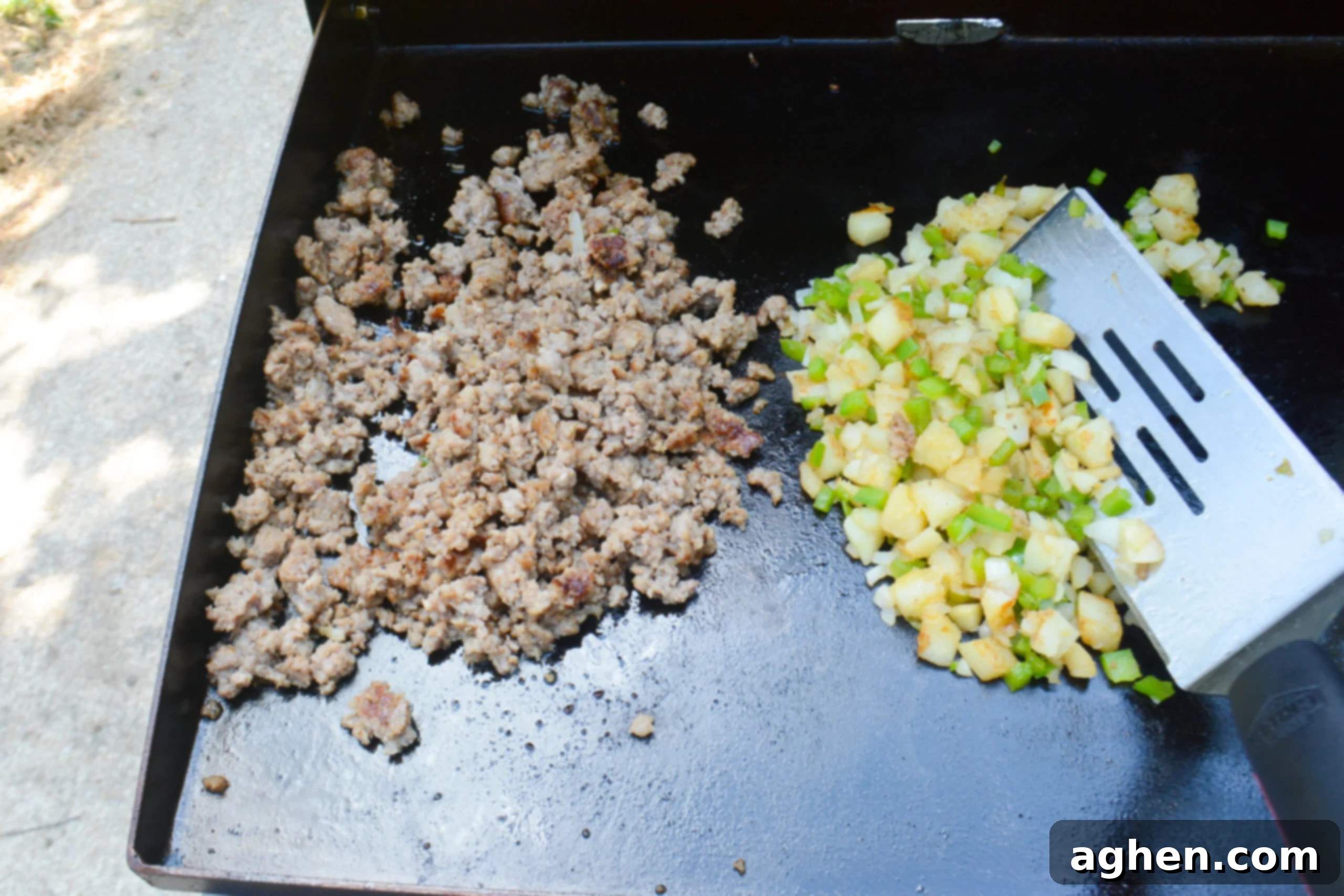 A large spatula folds the veggie mixture into the cooked sausage 