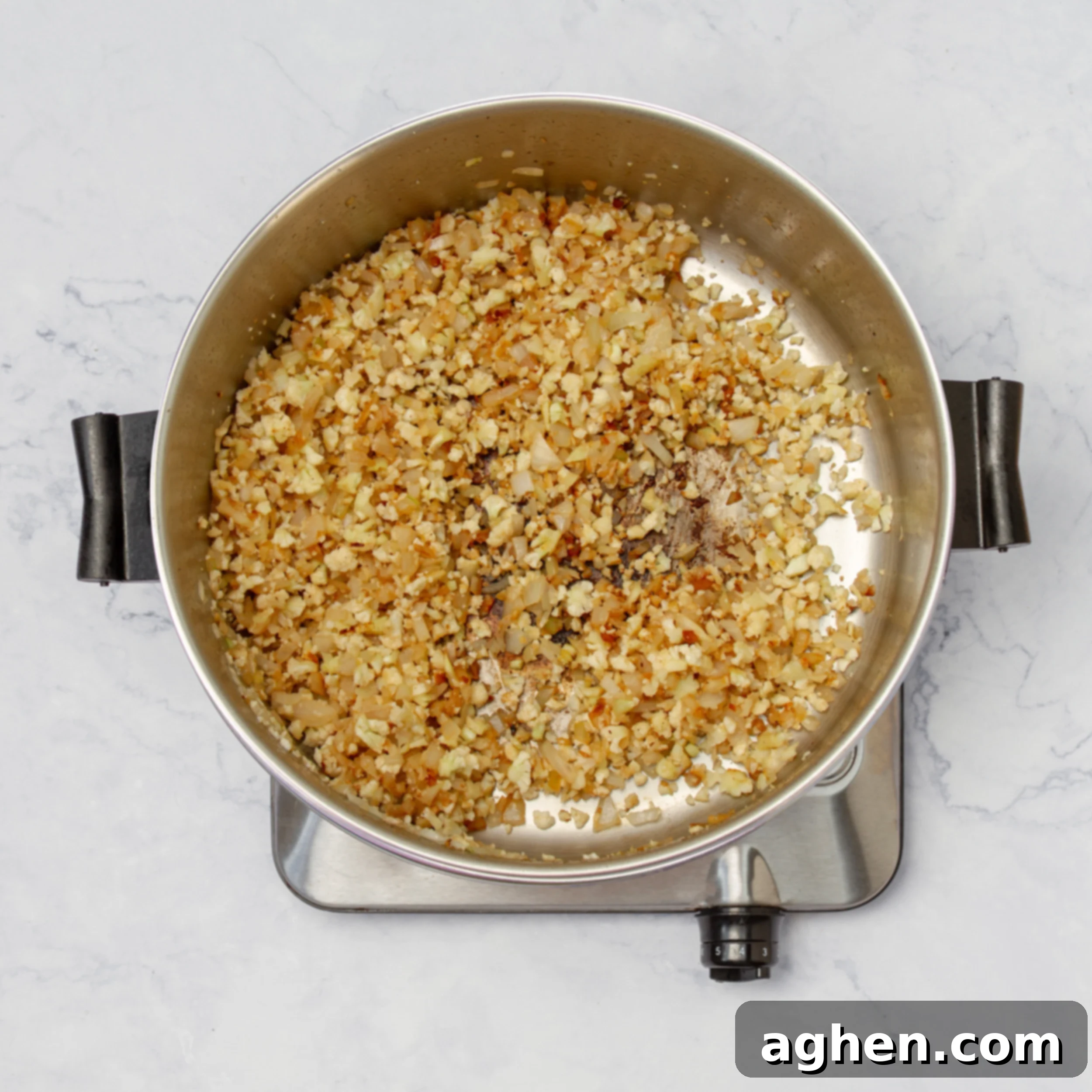 Onions, garlic, and cauliflower rice sautéing in a hot pan, releasing their aromatics.