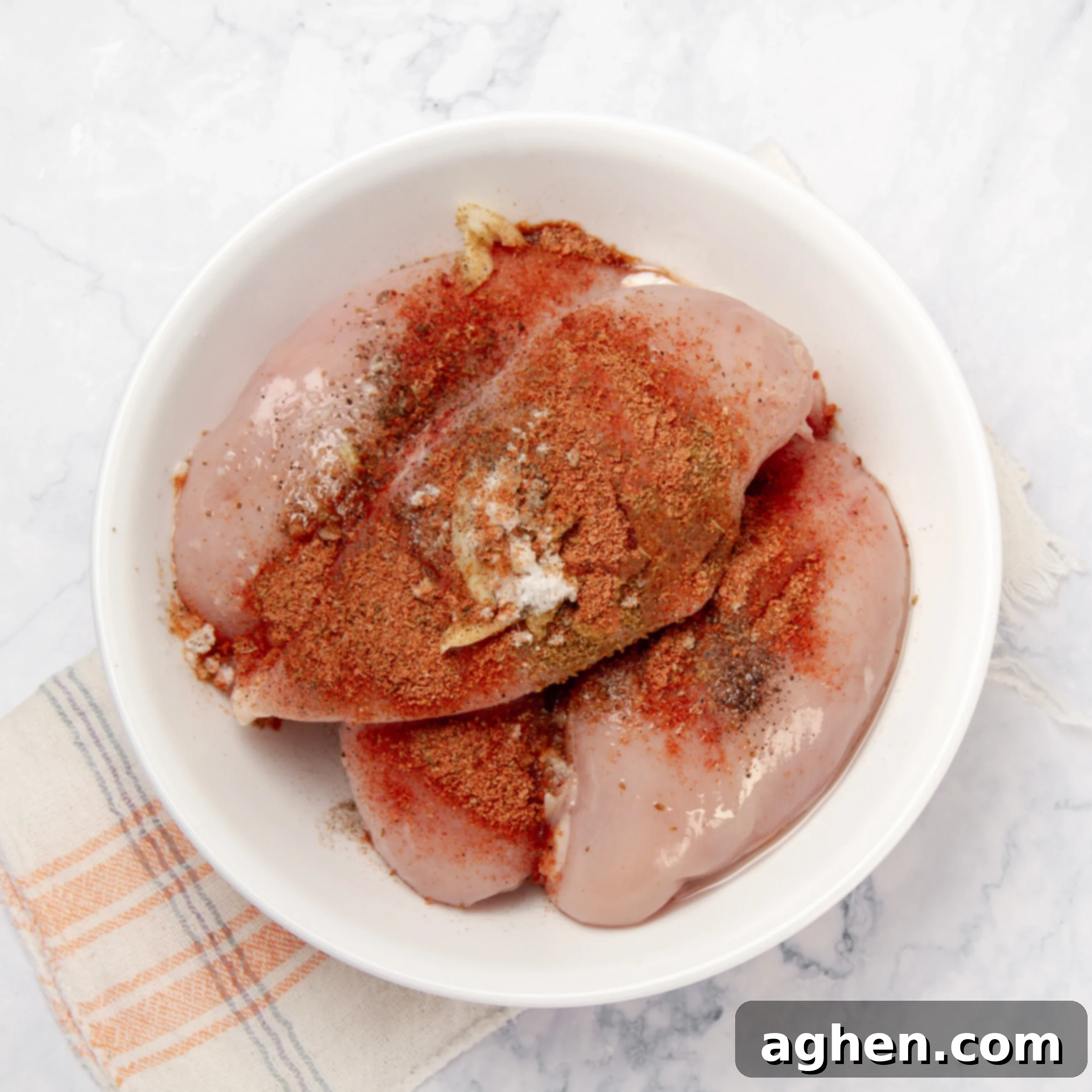 Small dish of chicken with a variety of seasonings ready to be rubbed into the meat.