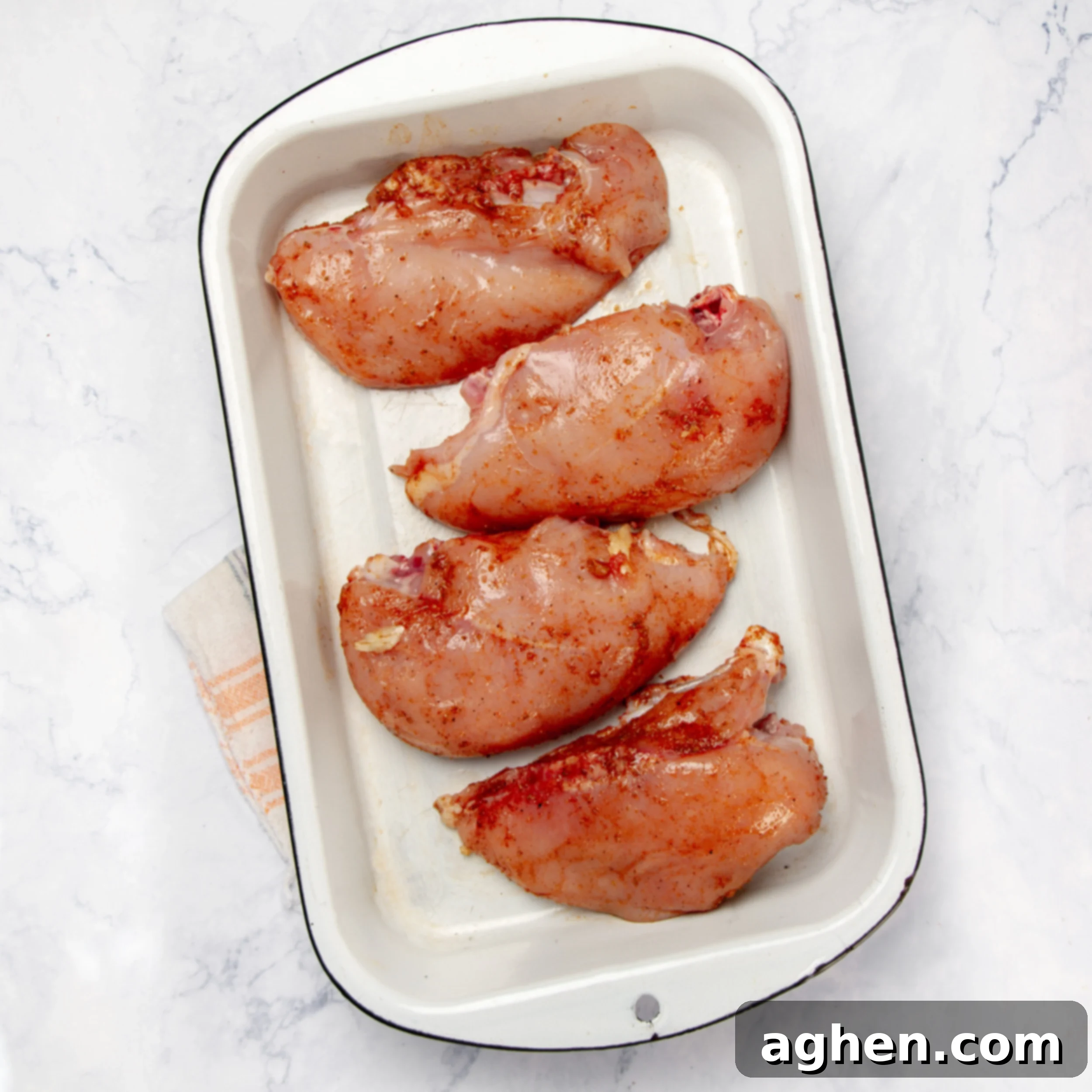 Seasoned chicken breasts neatly arranged in a casserole dish, ready for the next layer.