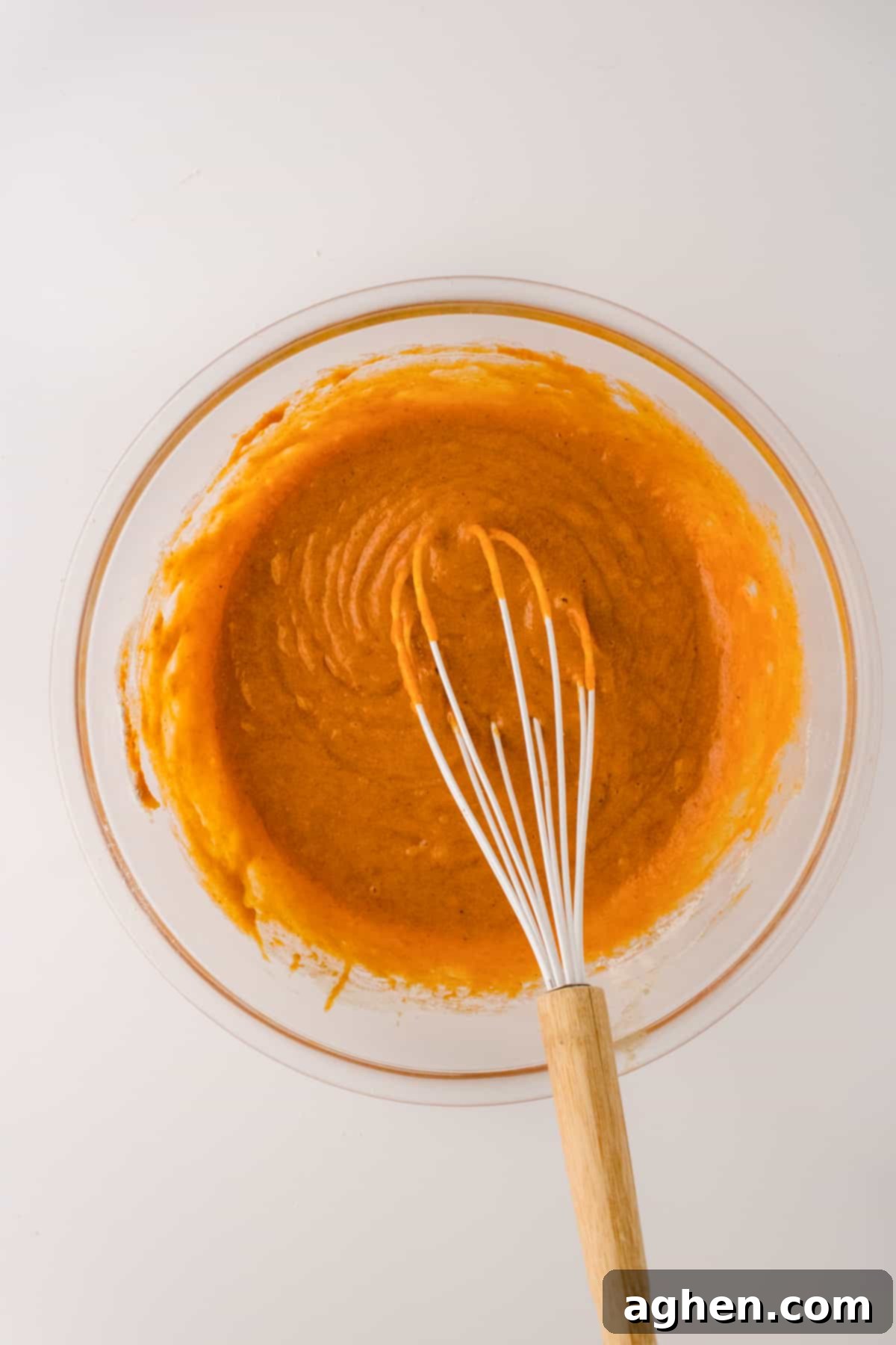 Autumn Pumpkin Cream Cheese Roll 4 Smooth pumpkin cake batter in a glass bowl with a wire whisk, ready for baking.