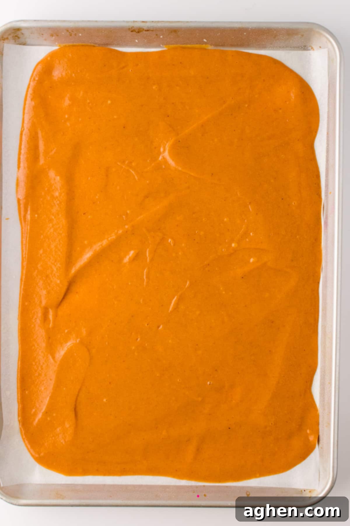 Autumn Pumpkin Cream Cheese Roll 5 Pumpkin spice cake batter spread evenly in a parchment-lined baking sheet pan, ready for the oven.