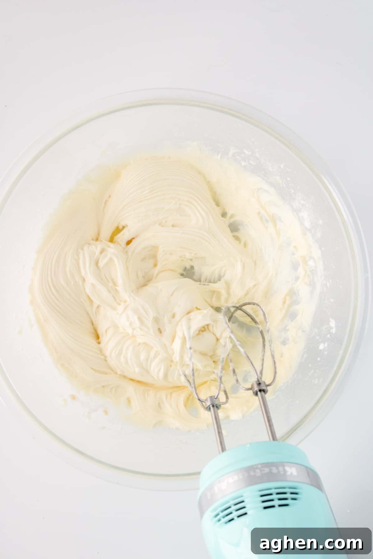 Autumn Pumpkin Cream Cheese Roll 9 Cream cheese filling being whipped to a smooth consistency in a glass bowl using a hand mixer.