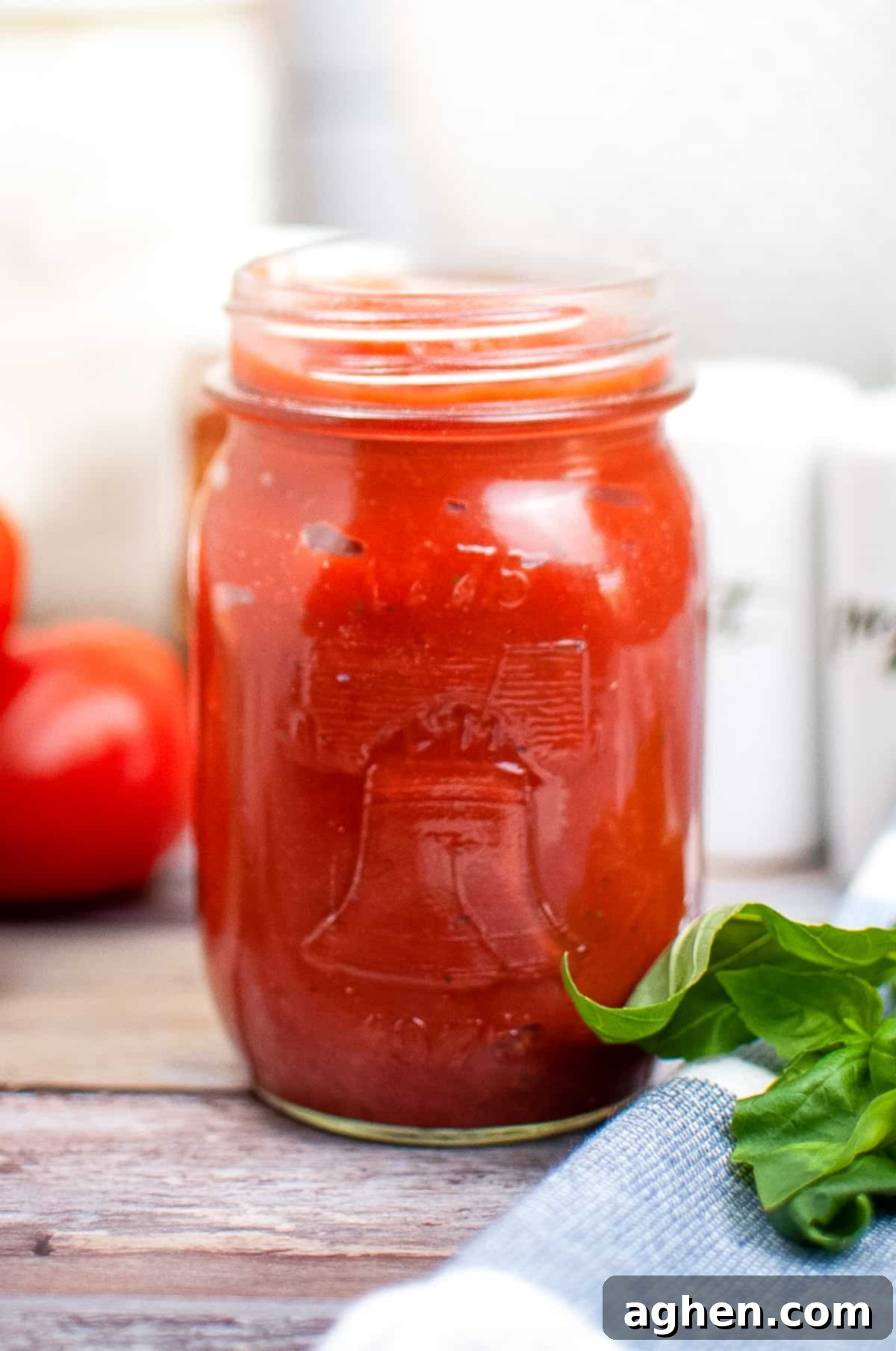 Homemade pizza sauce from tomato pasta in a mason jar on a wooden table.