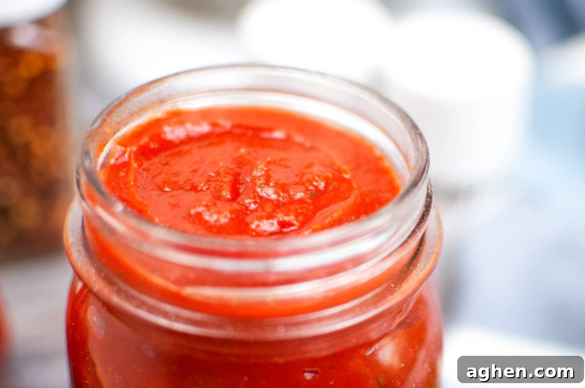 Close up photo of thick pizza sauce in a glass jar.