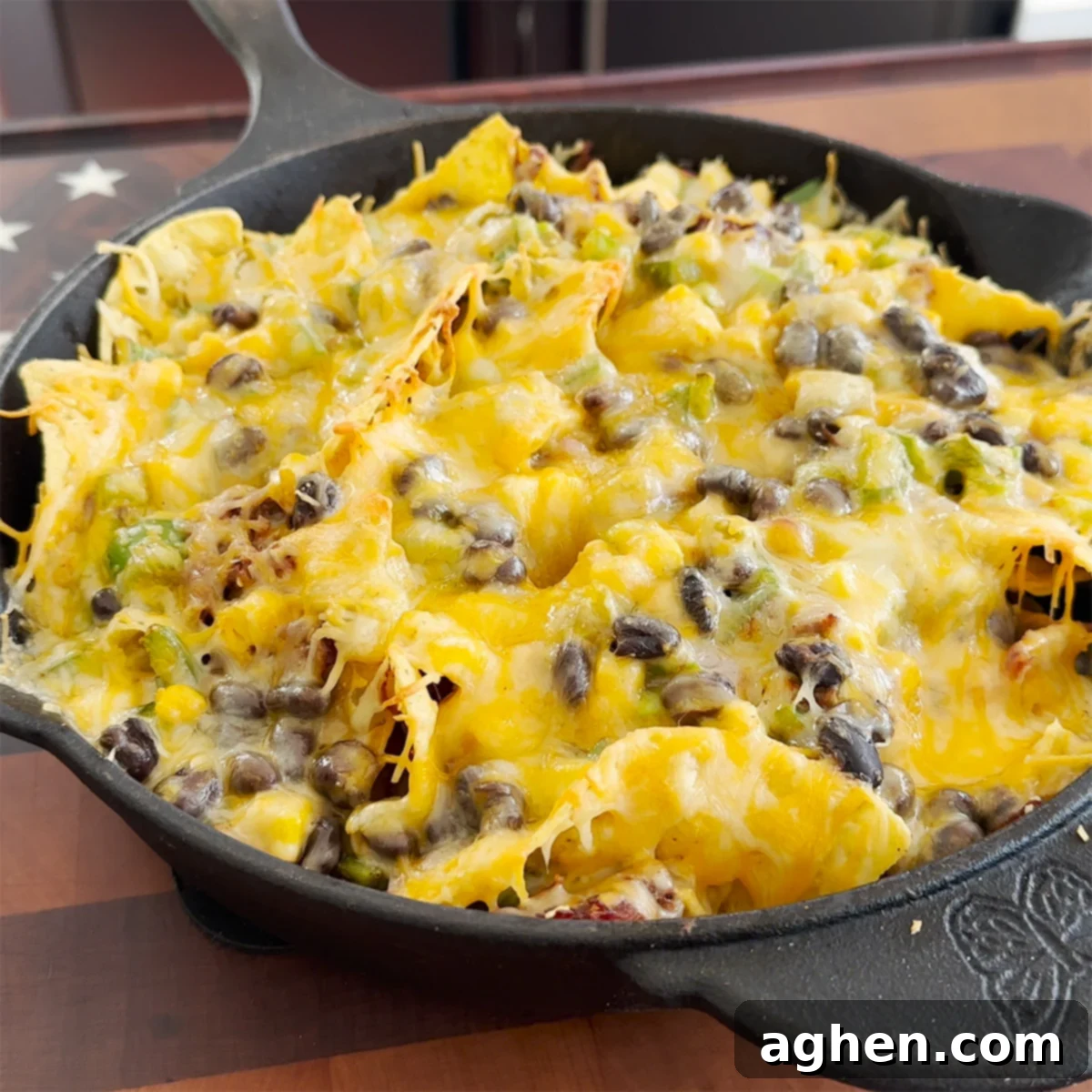 A large cast iron skillet filled with delicious Traeger Cast Iron Nachos, loaded with pulled beef, melted cheese, and fresh vegetables, ready for serving.