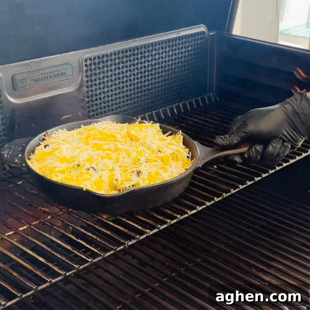 The finished Traeger Cast Iron Nachos in a skillet, fresh off the grill with perfectly melted and bubbly cheese.
