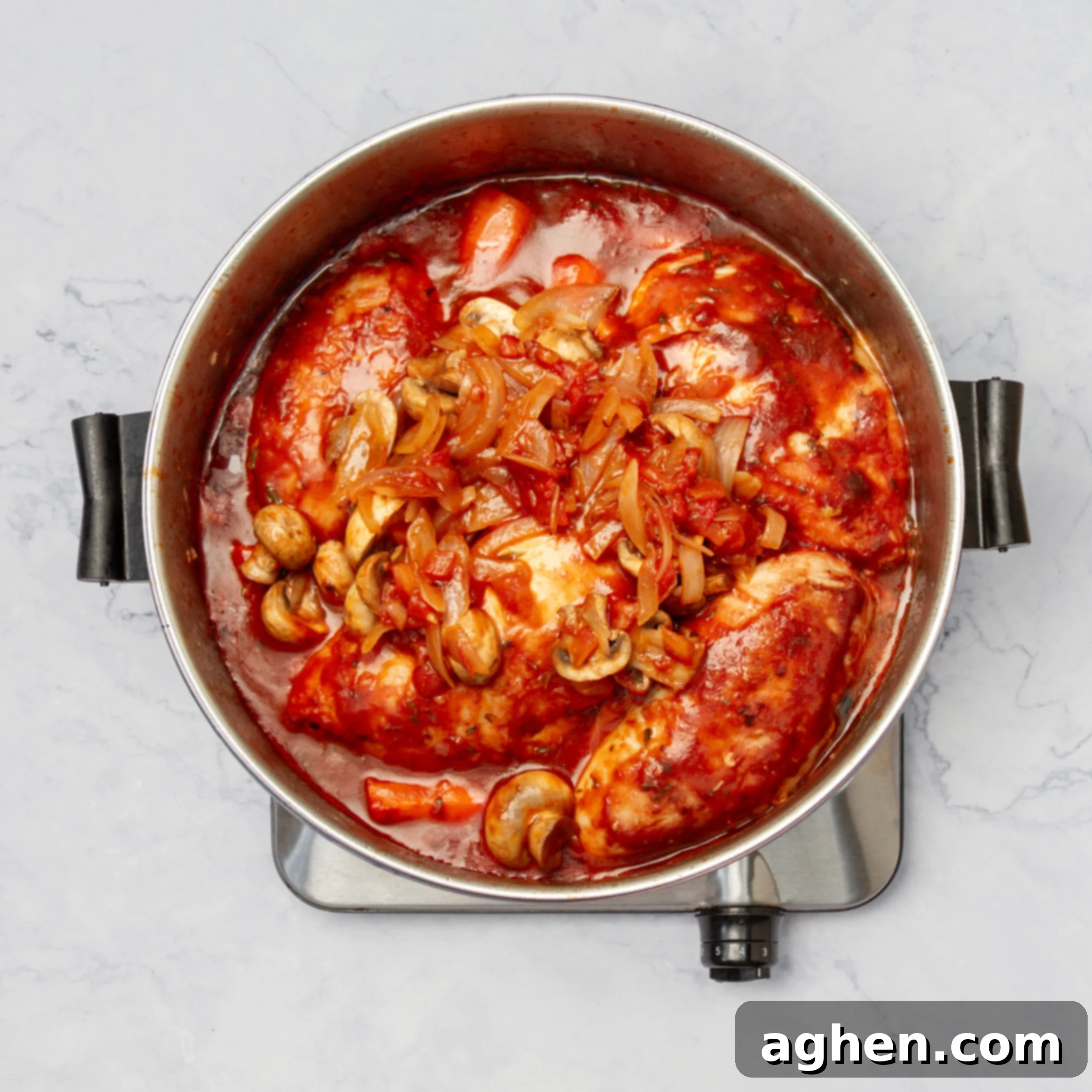 Cooked chicken, vegetables, and sauce simmering in a pot. 